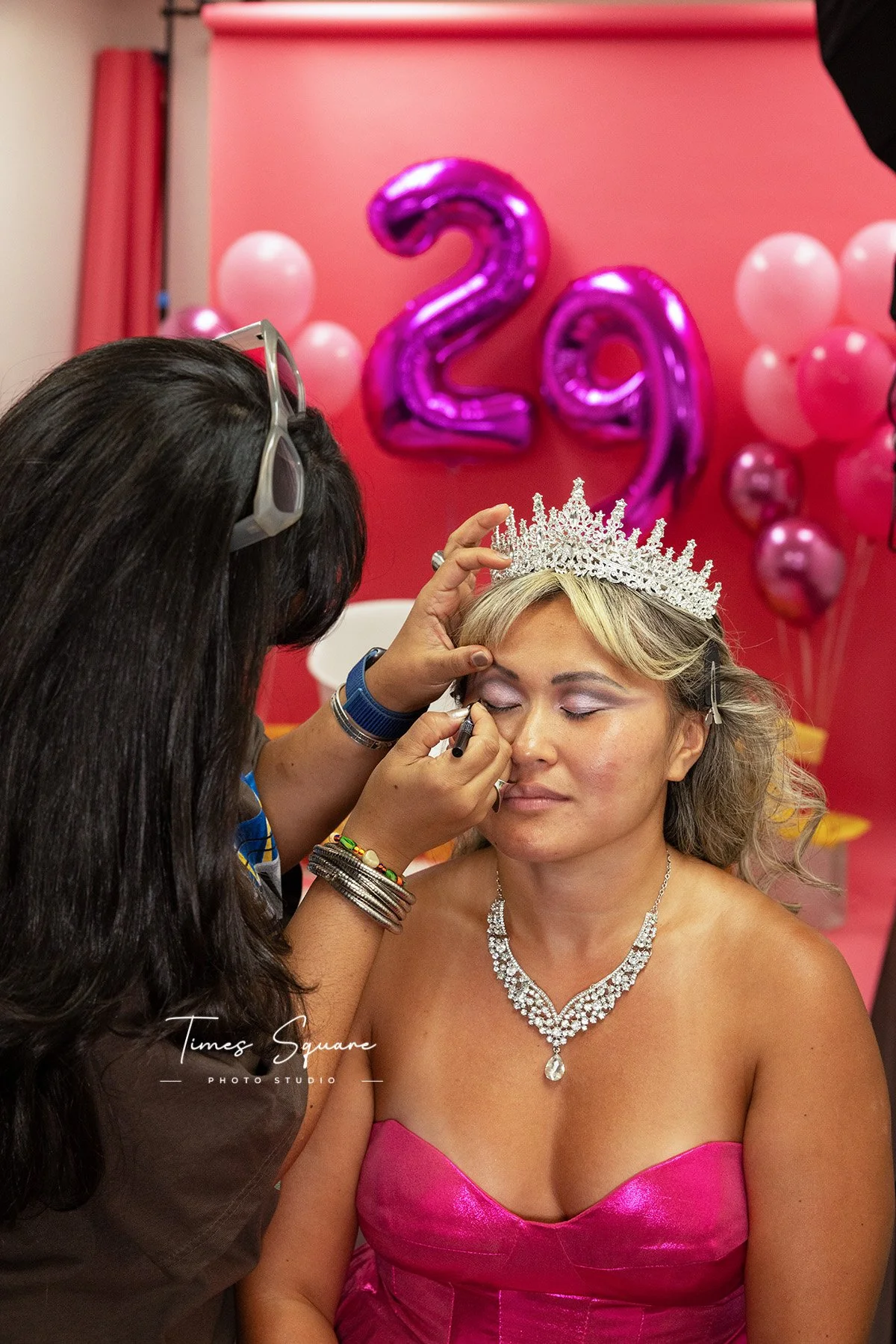 a woman getting her makeup done for her birthday studio photoshoot in New York City. All pink maximalist birthday photoshoot