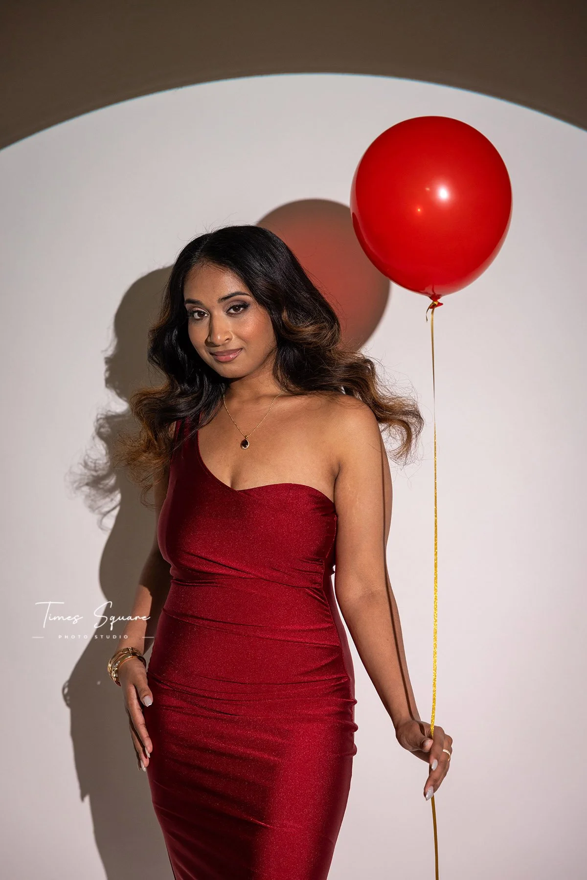 Fashion-inspired birthday photoshoot in a NYC studio featuring elegant posing, bold lighting, and a red celebration balloon.