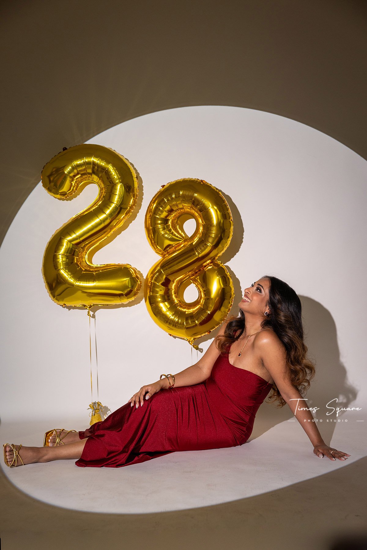 a woman posing with gold mylar balloons for her birthday studio photoshoot in New York City