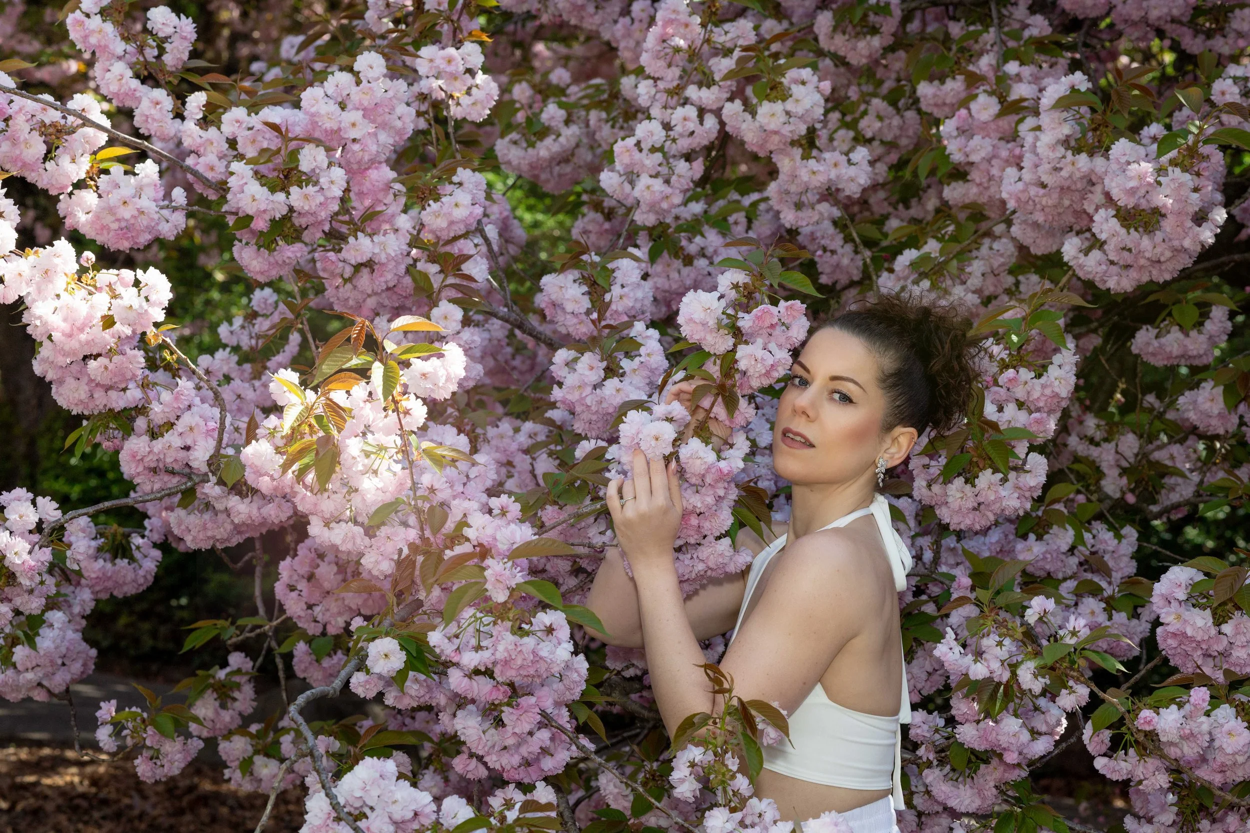 Lifestyle portrait of a woman during cherry blossom season at Brooklyn Botanic Garden in New York City.