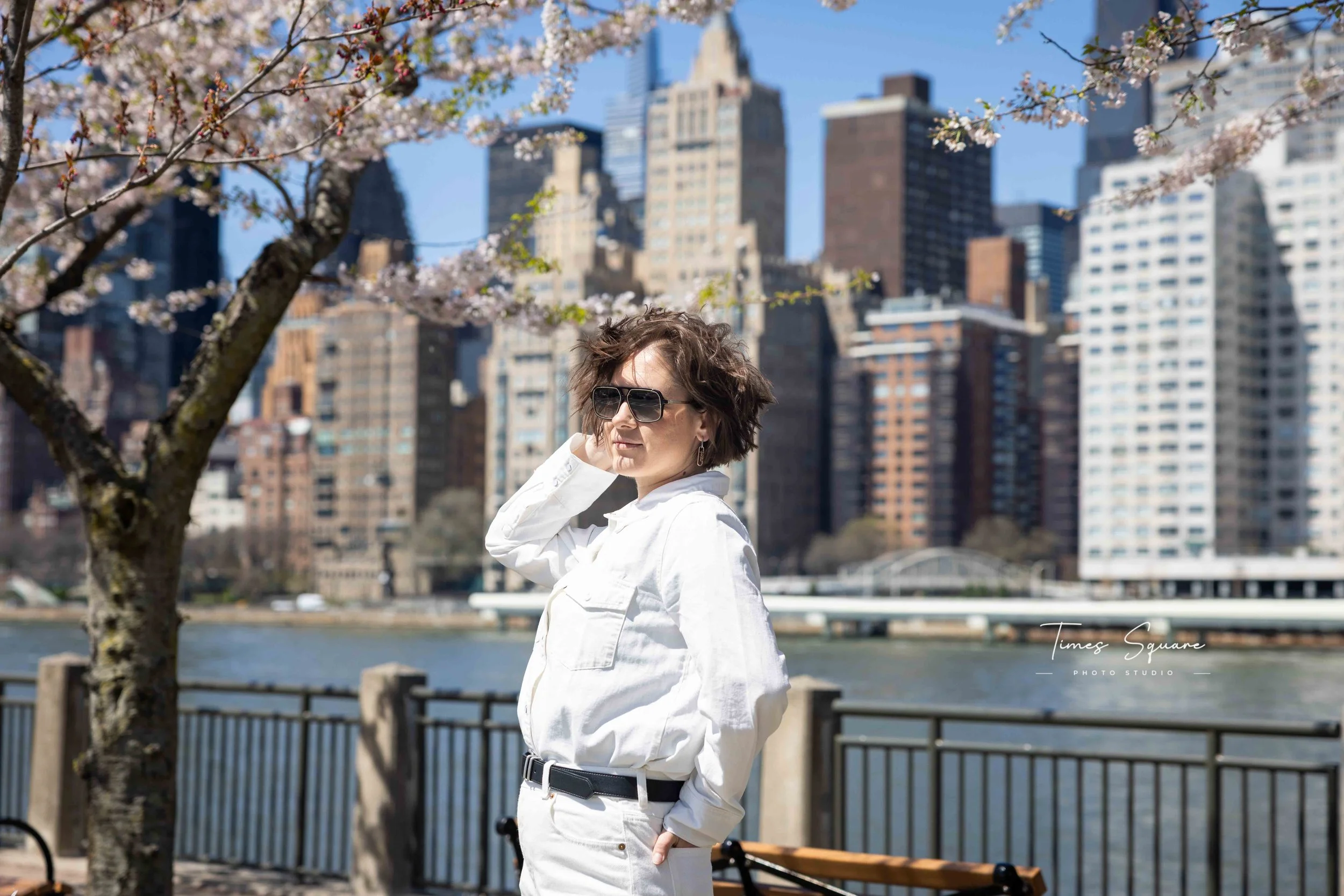 Spring portrait session with cherry blossoms and Manhattan skyline views on Roosevelt Island in New York City.