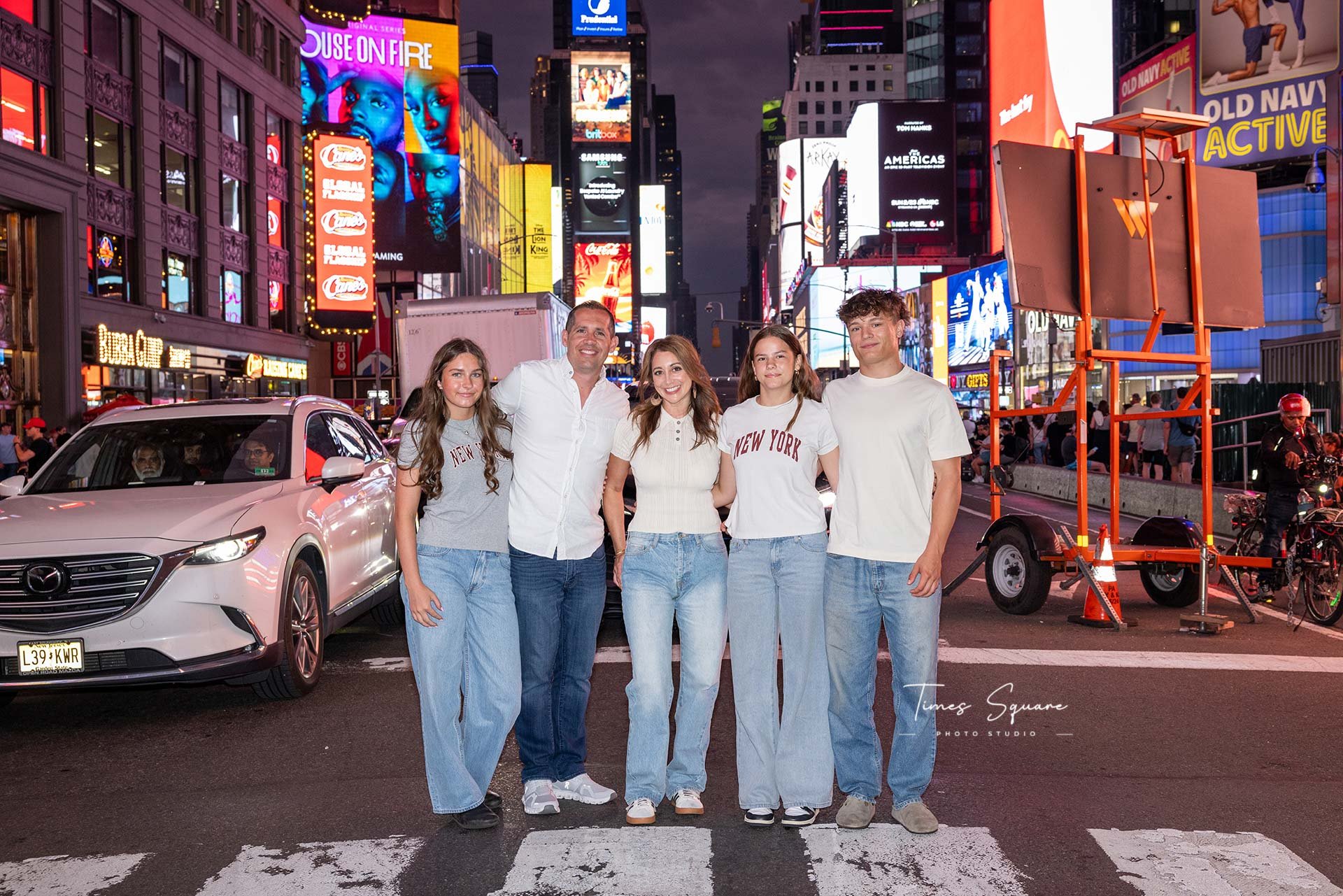A family during a vacation photoshoot in Times Square at night with bright signs and billboards in the background