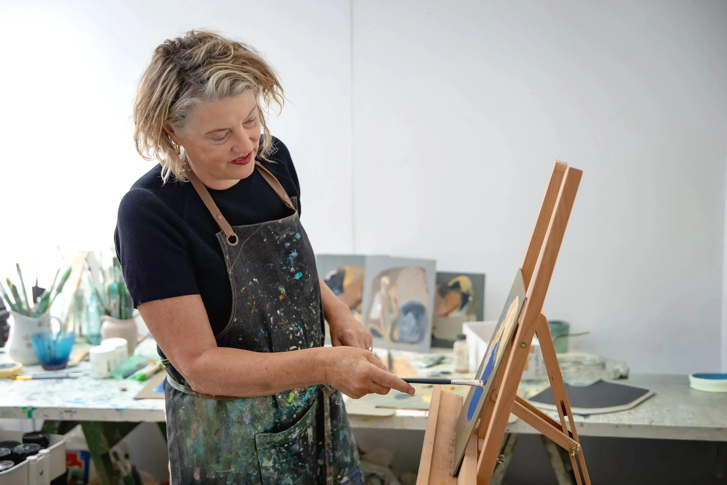 Australian artist Anne-Rita Vleugel working in her studio on an oil painting.