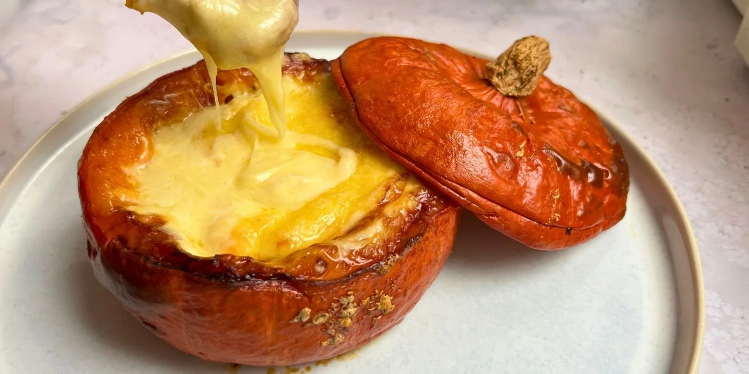 Aufgeschnittener Hokkaido, gefüllt mit geschmolzenem Camembert, Brot zum Dippen