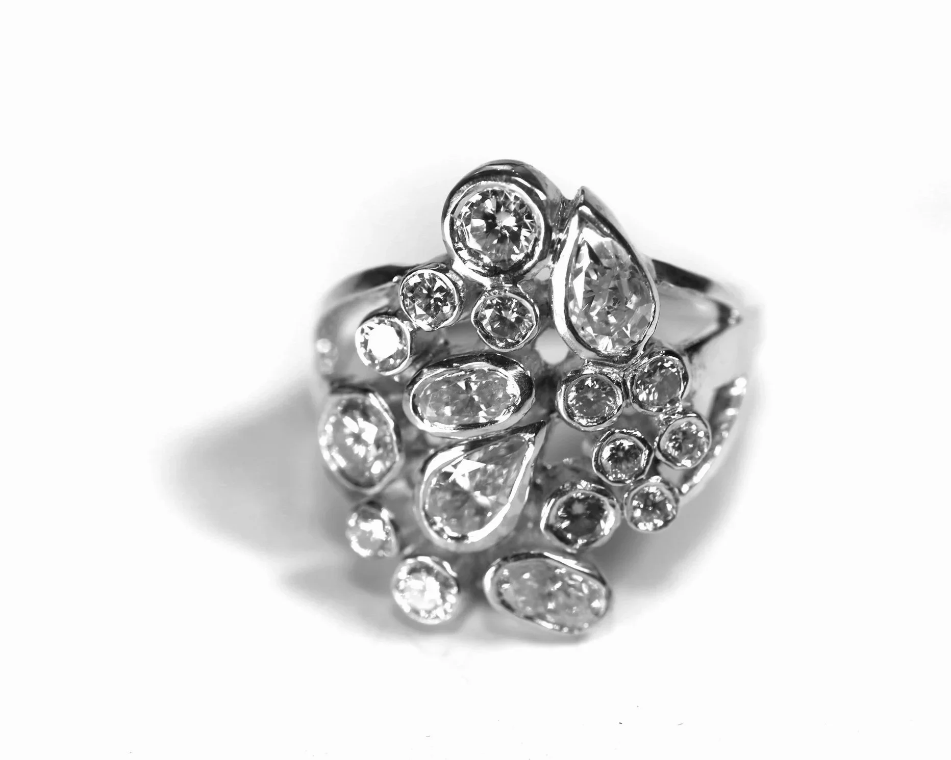 Close-up of a silver ring with multiple embedded diamonds in a floral design.
