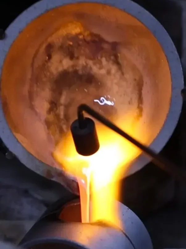 The alchemy of sand-casting: molten gold being poured into a custom landscape mold by goldsmith Iain Sainsbury PhD .