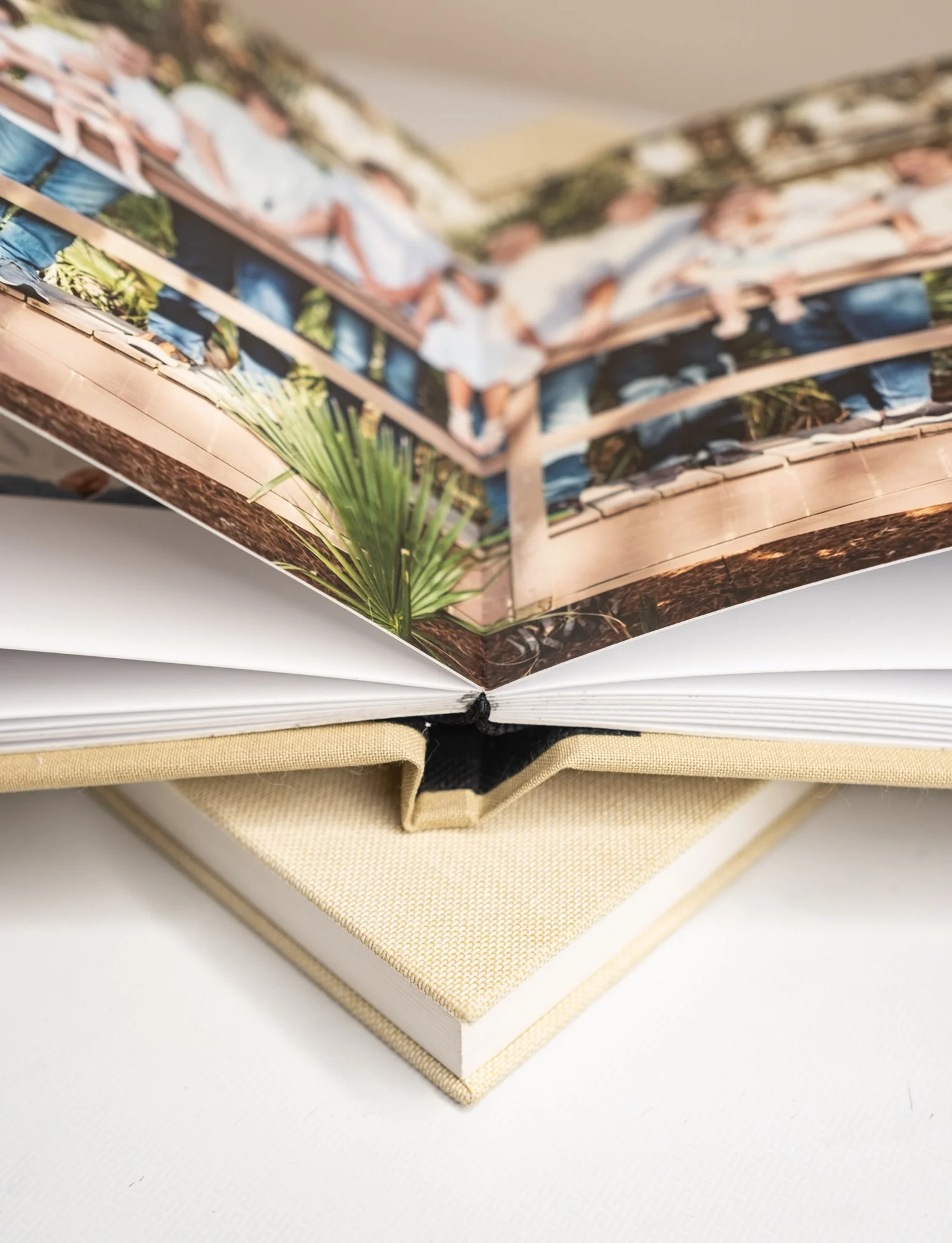 Open photo album with a blurred image of people on a bridge, resting on another closed beige album.