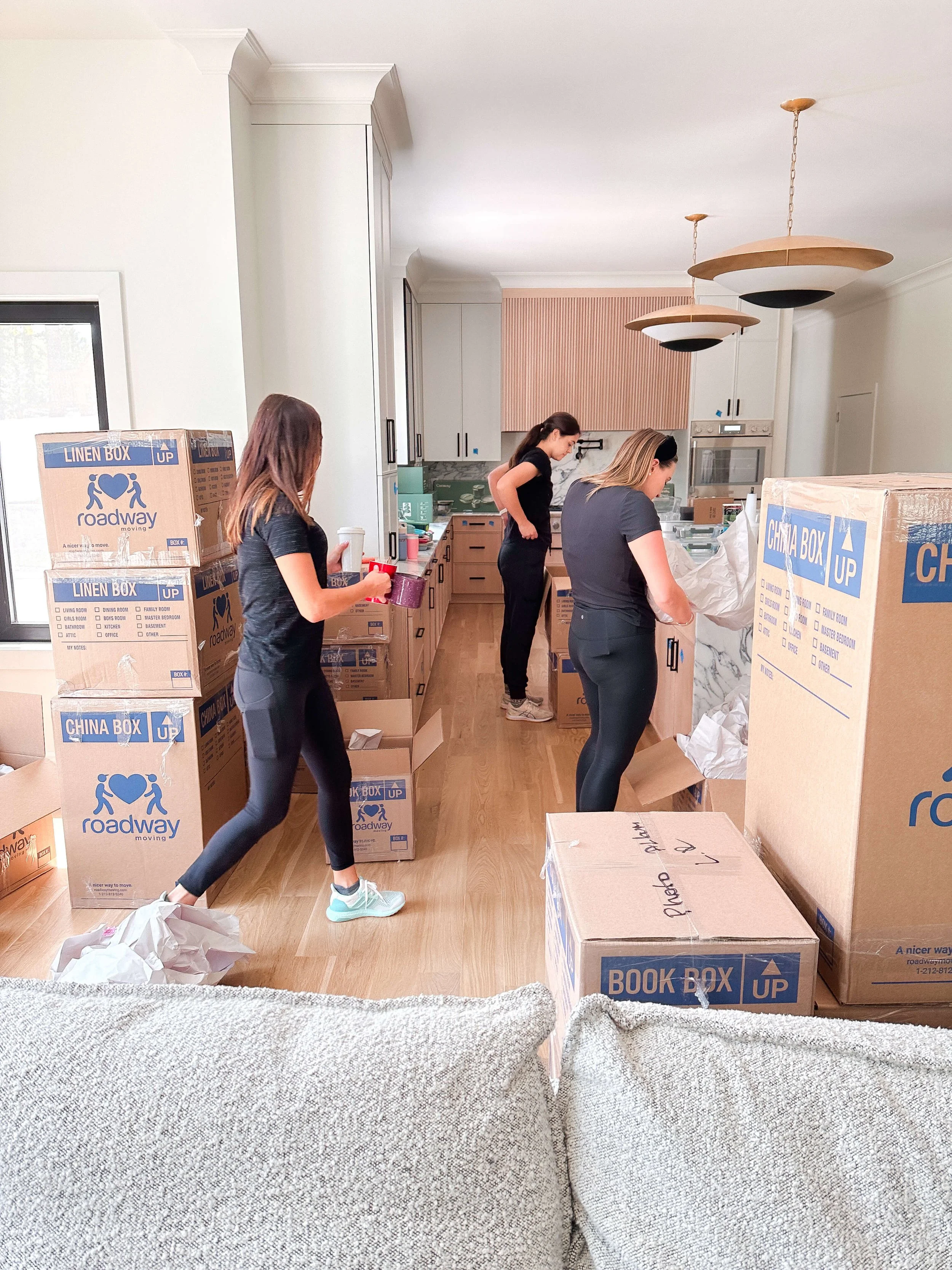 Simplify Studio professional organizers unpacking moving boxes and setting up a client's kitchen