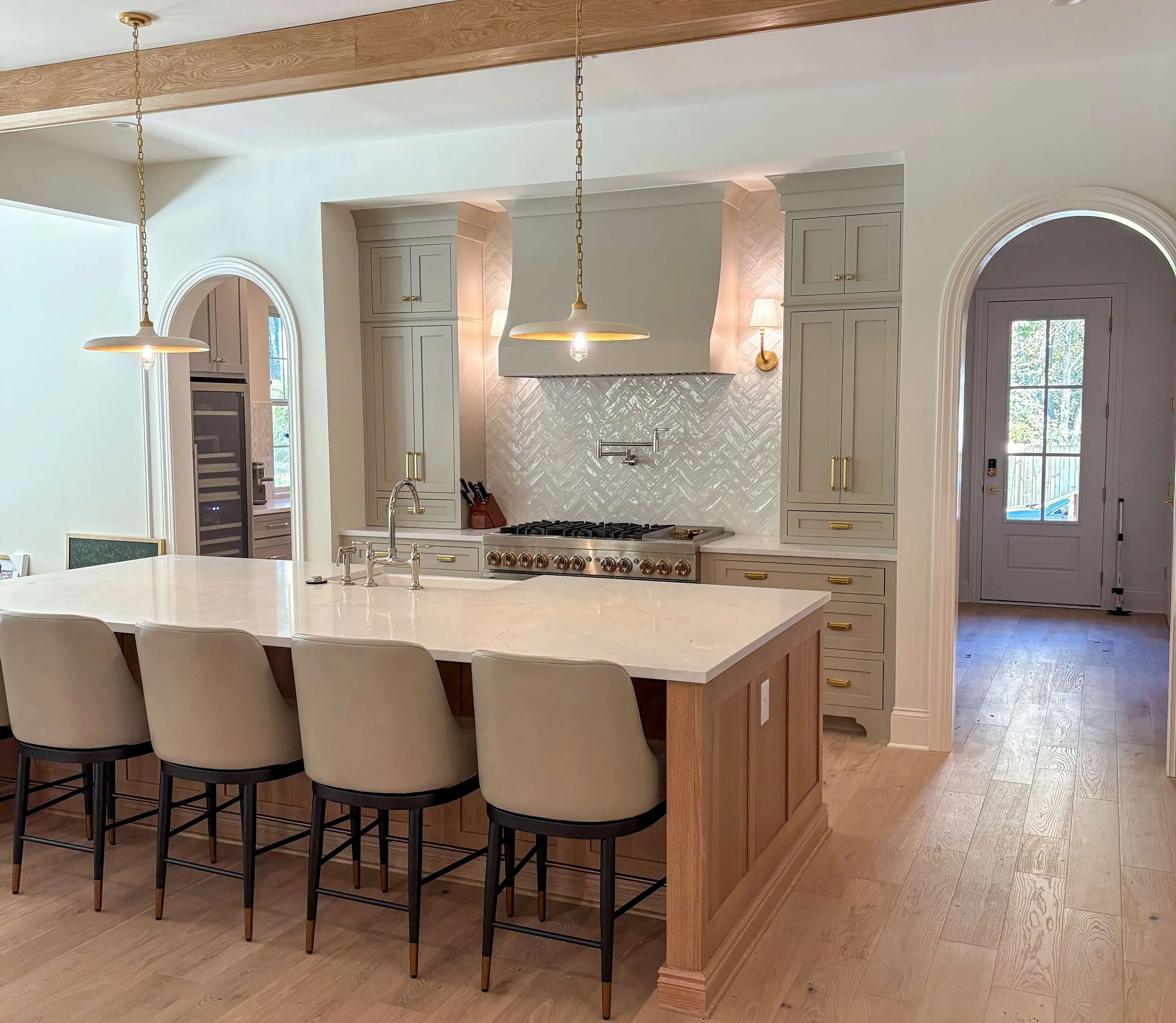 A calm, open kitchen with a large island, light wood floors, and uncluttered counters, organized by Simplify Studio.