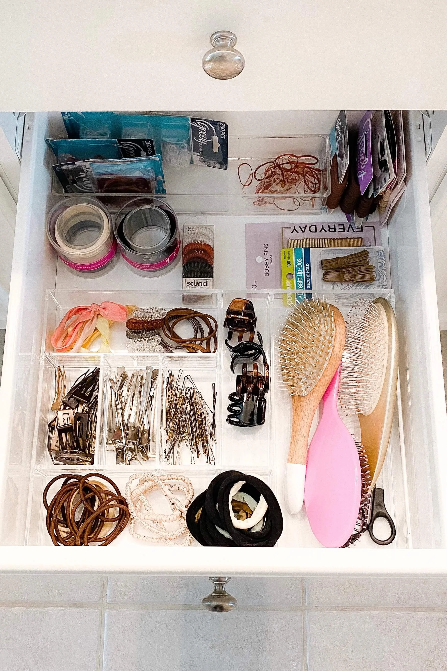 Organized bathroom drawer with hair accessories organized in clear drawer dividers