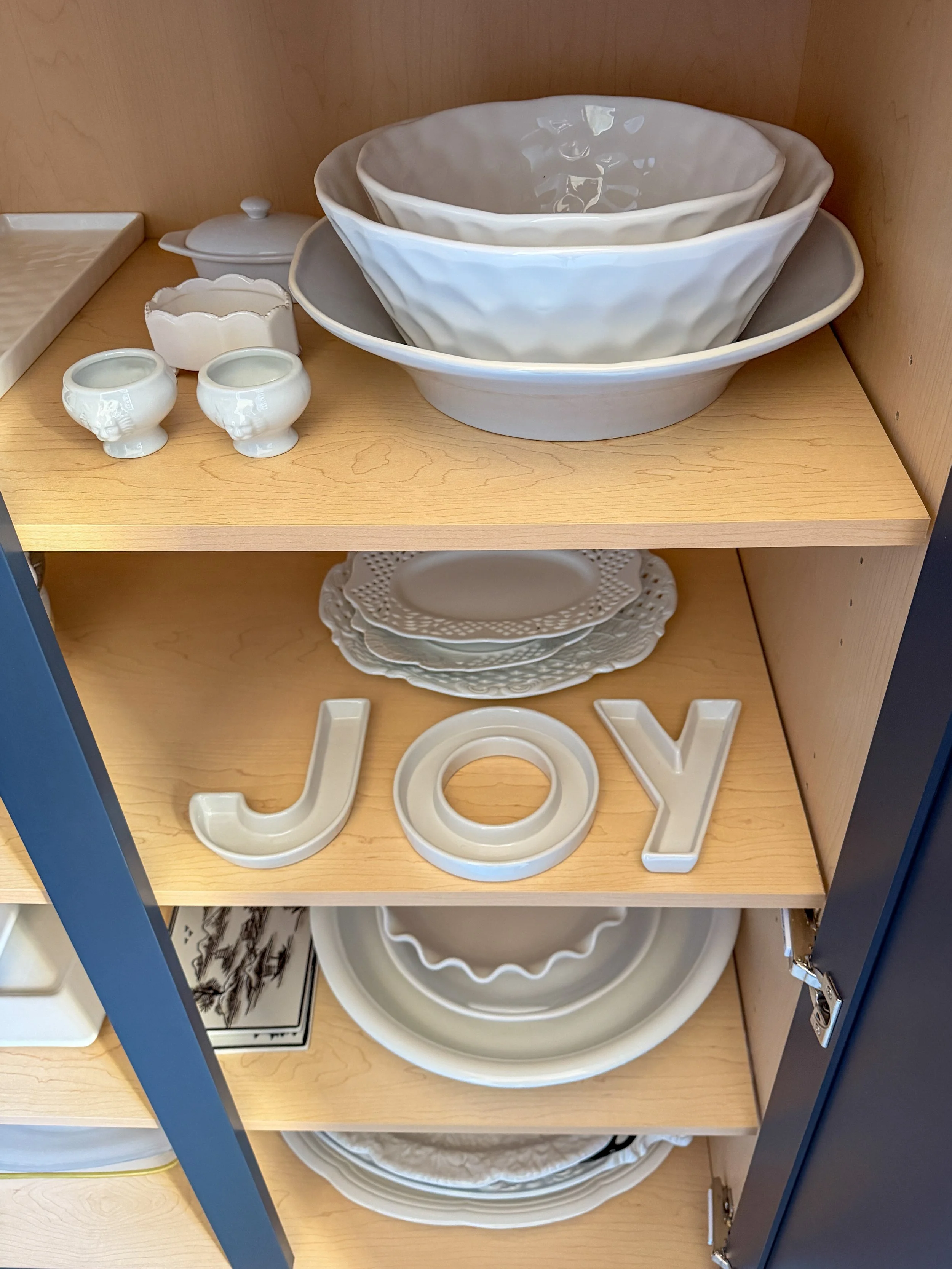 Organized kitchen cabinet with serving bowls and entertaining dishes.