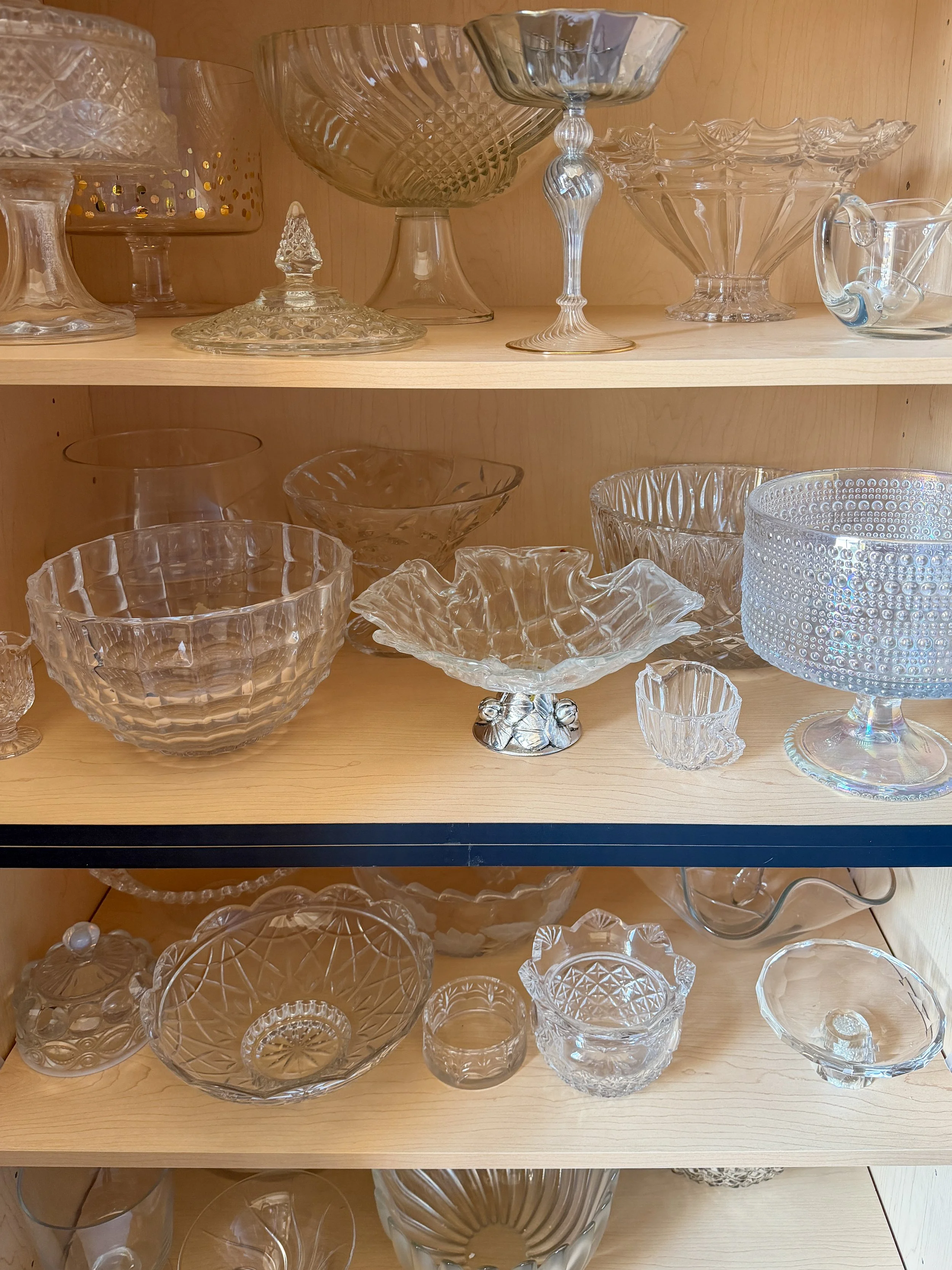 Glass serving bowls and dishes stored neatly inside a custom kitchen cabinet.
