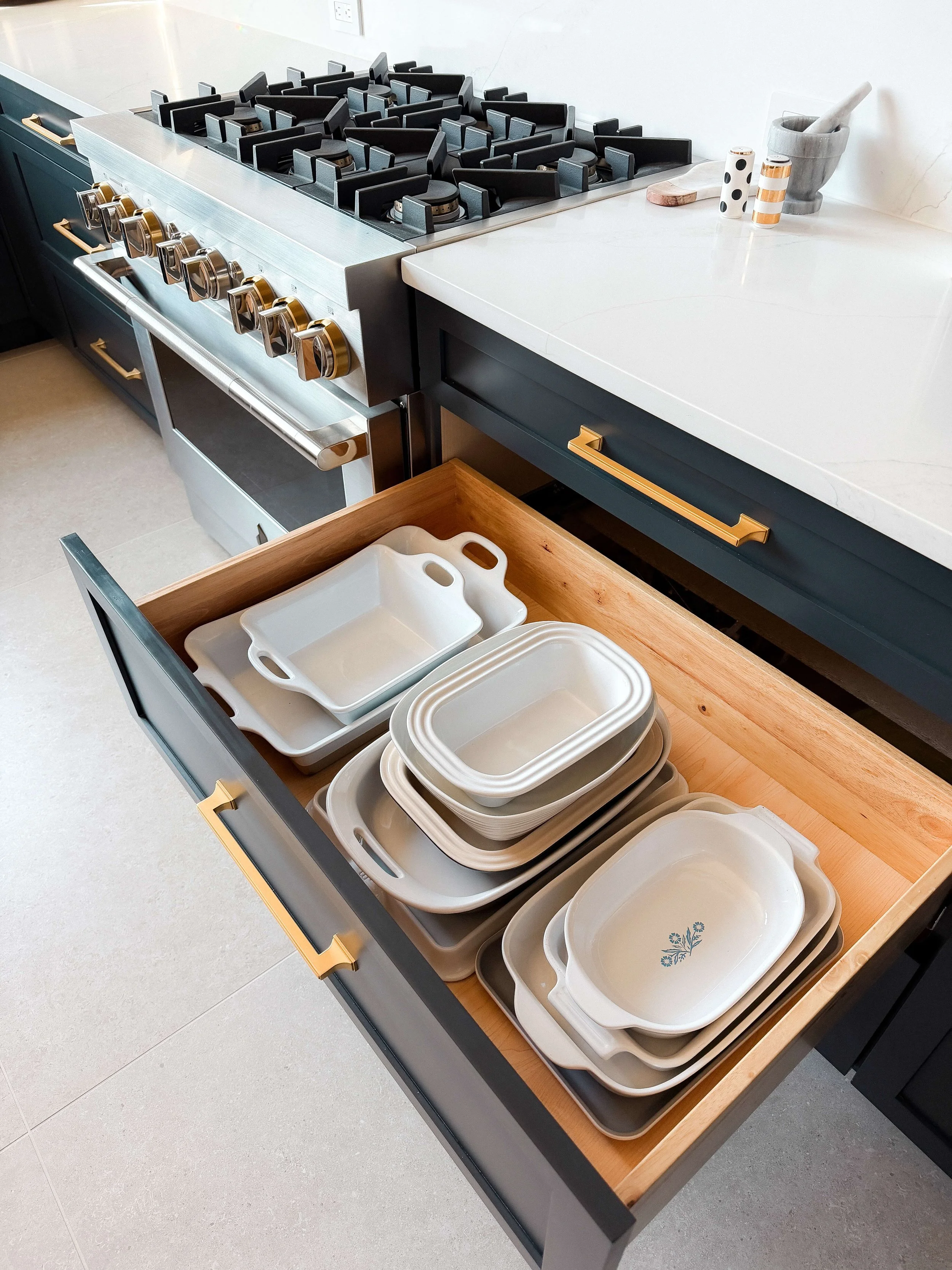 Deep kitchen drawer with baking dishes and casserole pans organized by size.