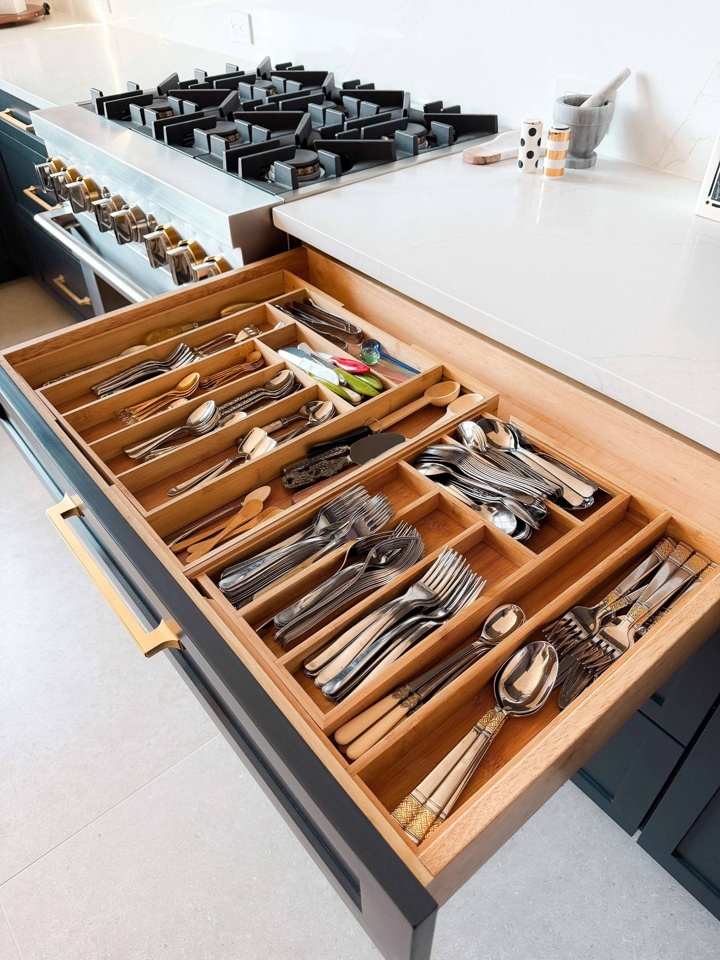 Kitchen utensil drawer with custom wood dividers organizing flatware and cooking tools.