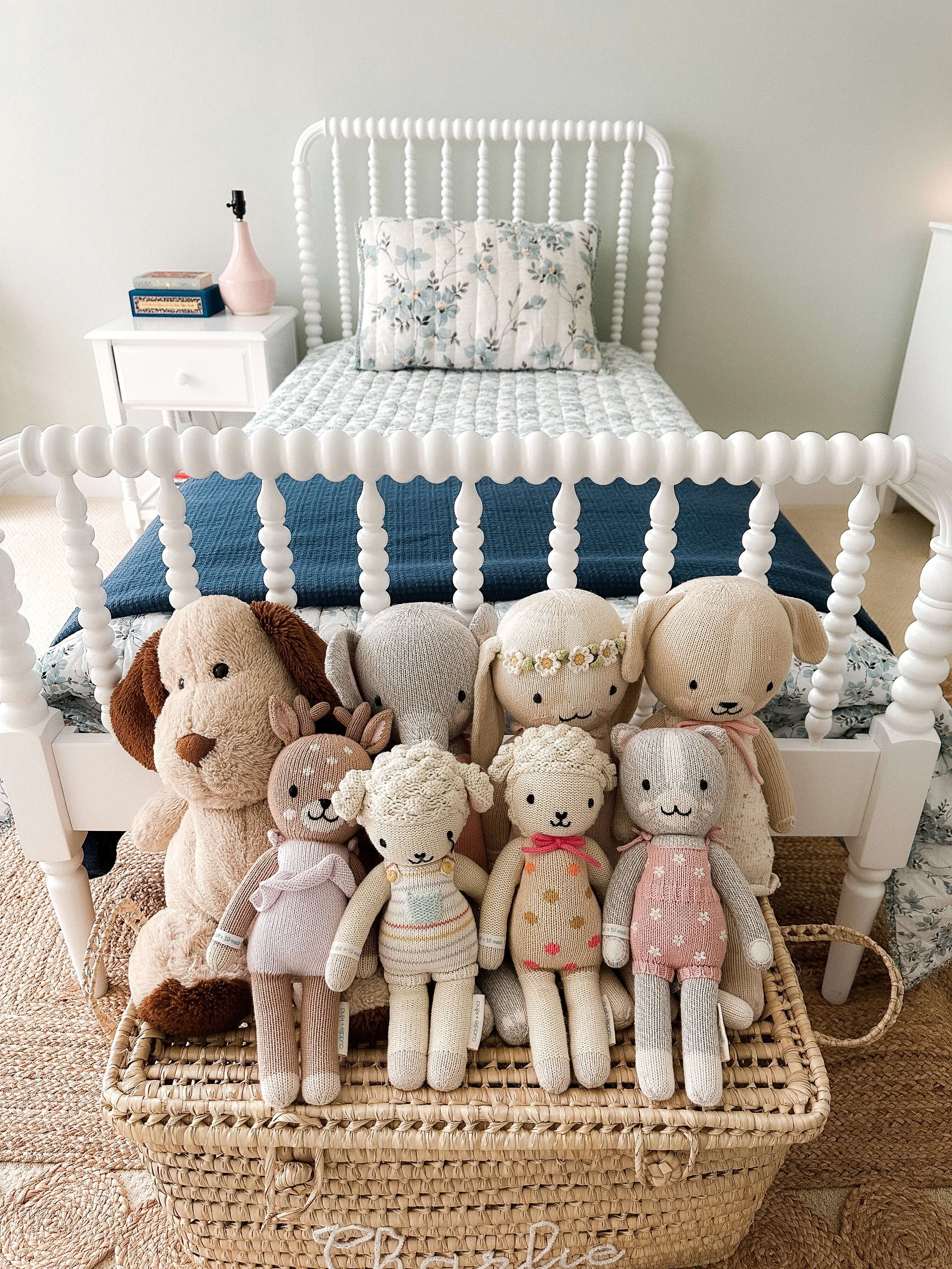 Stuffed animals organized in a labeled woven basket beside a child's bed in a Raleigh bedroom.