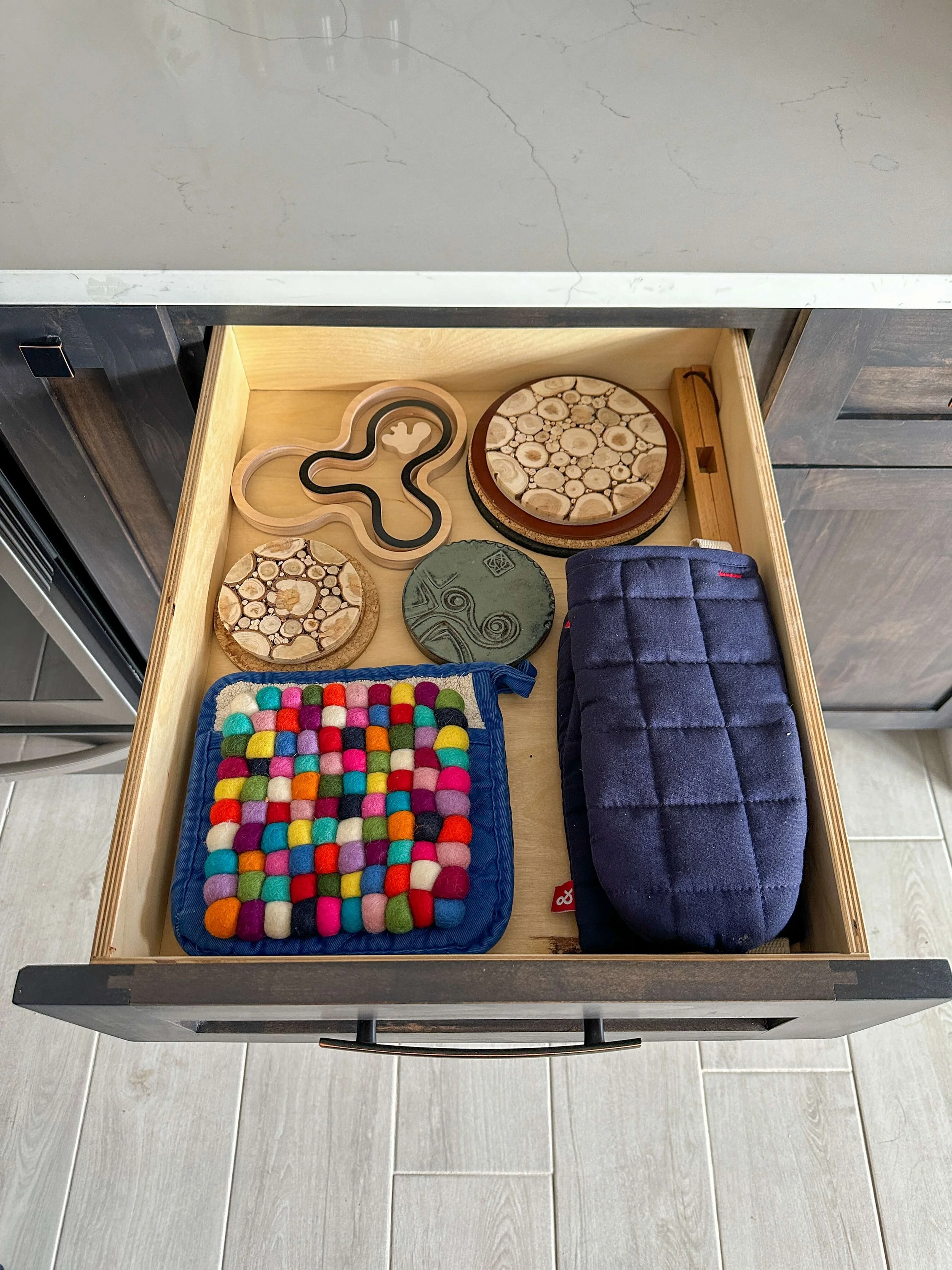 Kitchen drawer storing potholders, trivets, and hot pads in an organized layout.