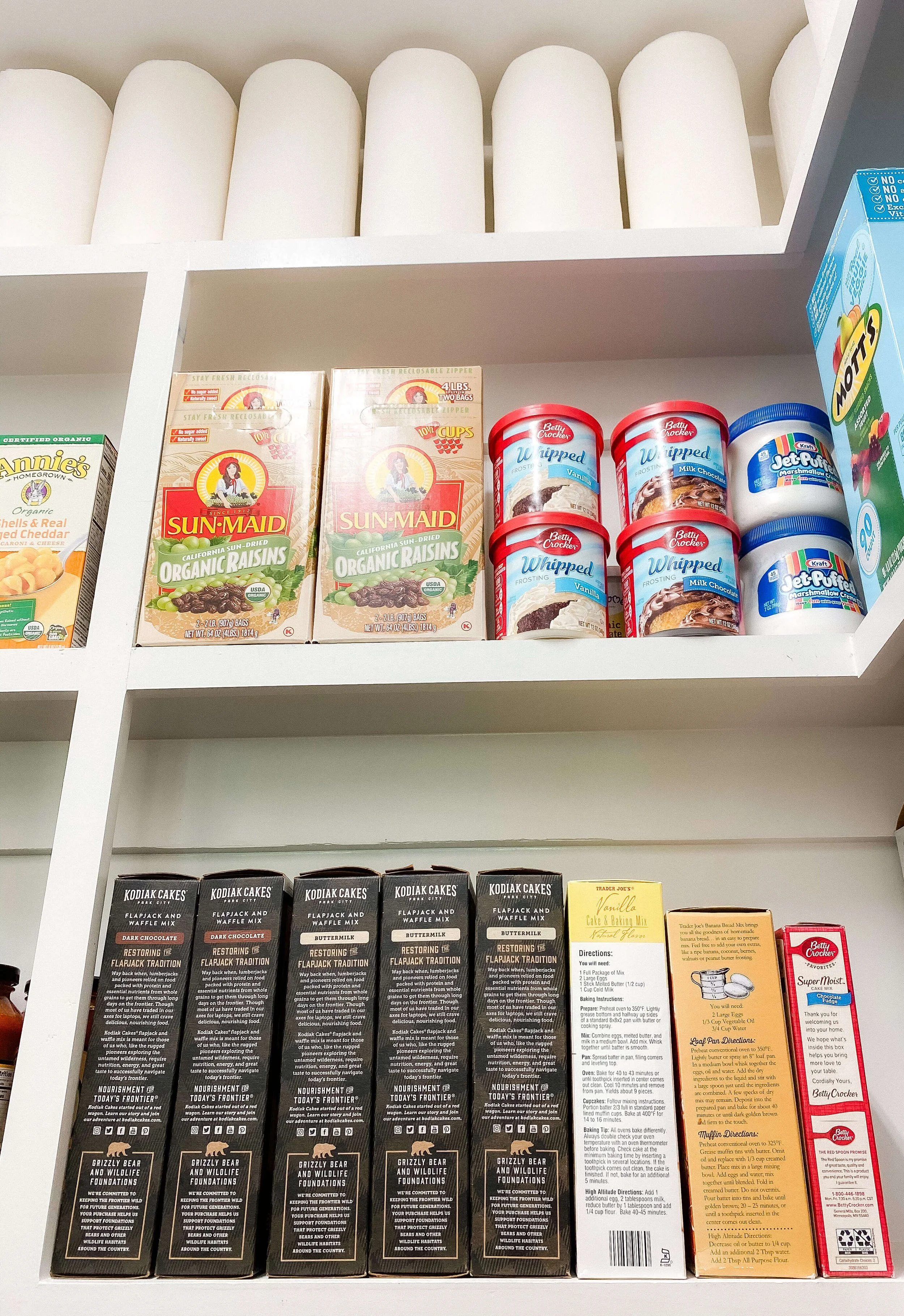 Pantry shelves organized with baking supplies and paper products.