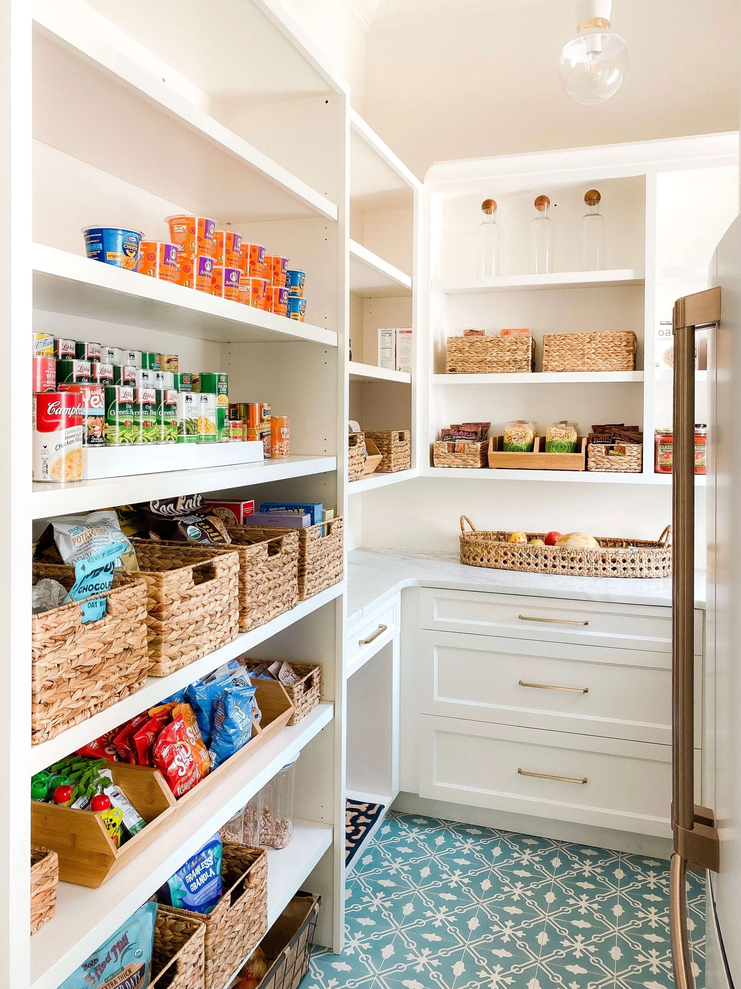 Organized walk-in pantry with baskets, shelving, and countertop storage.