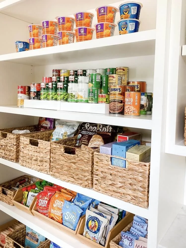 Modern walk-in pantry with open shelving, woven baskets, and organized food storage.