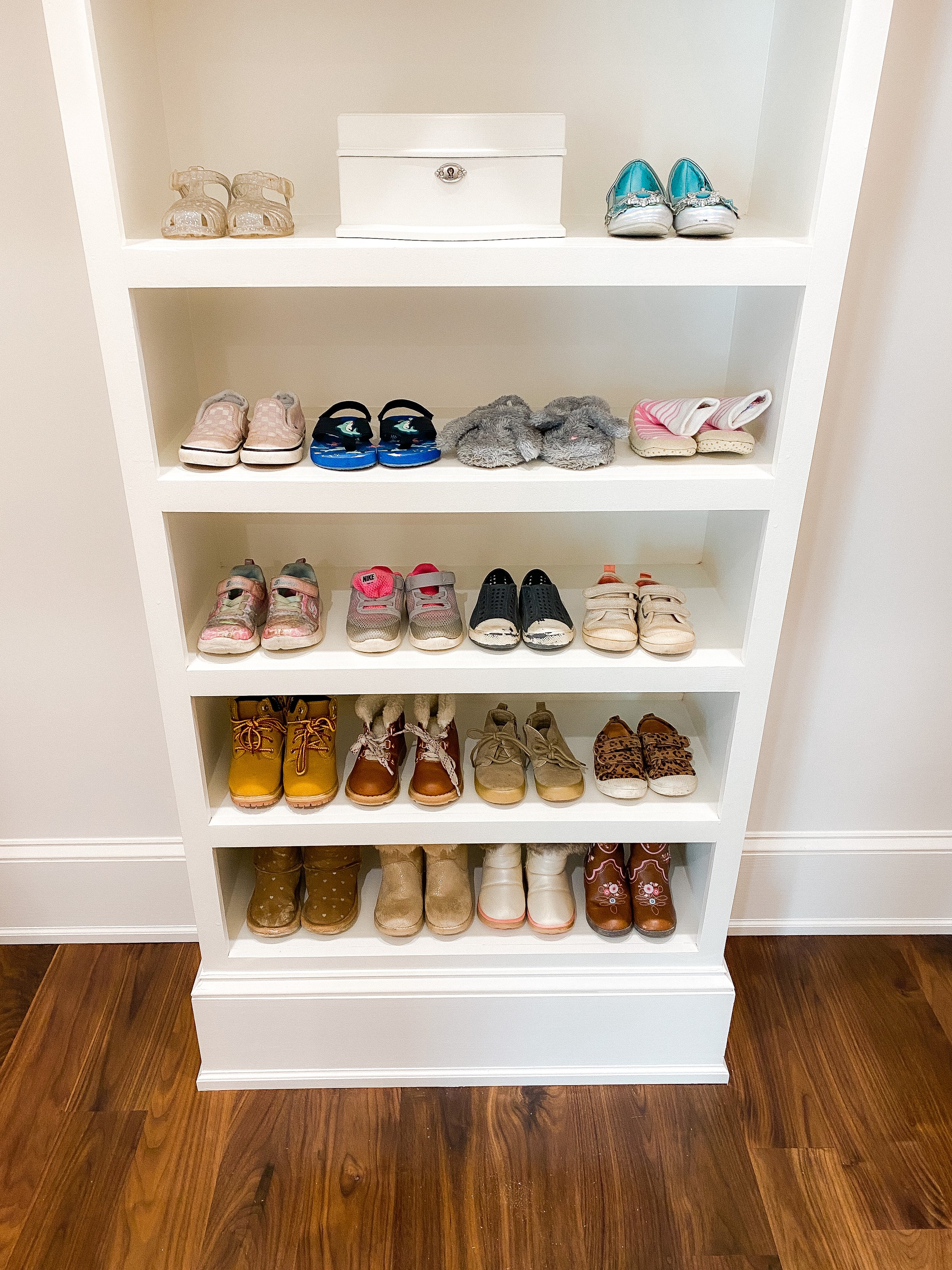 Children's shoes organized by size on open built-in shelving