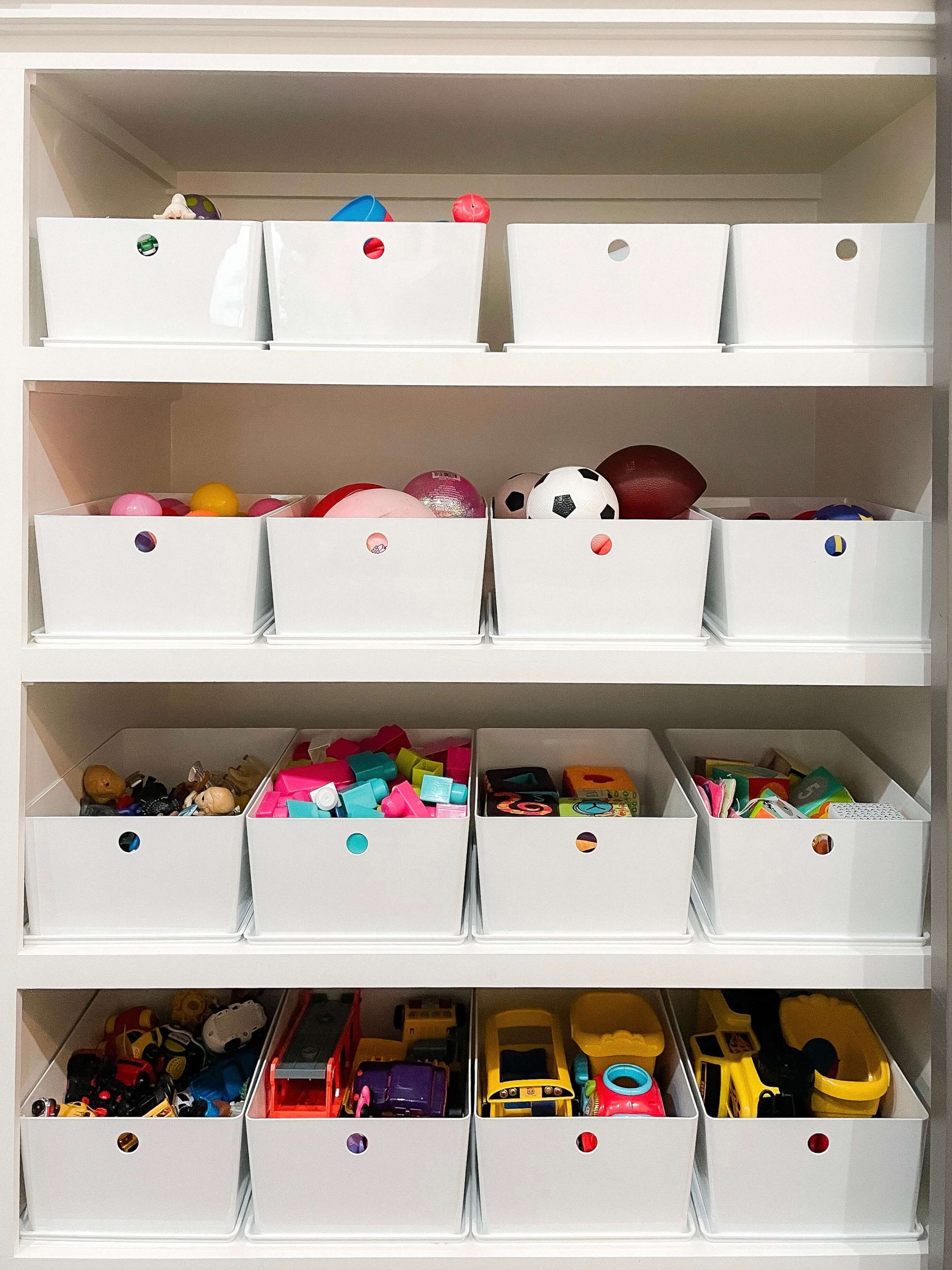 White storage bins organized by toy category on built-in playroom shelves