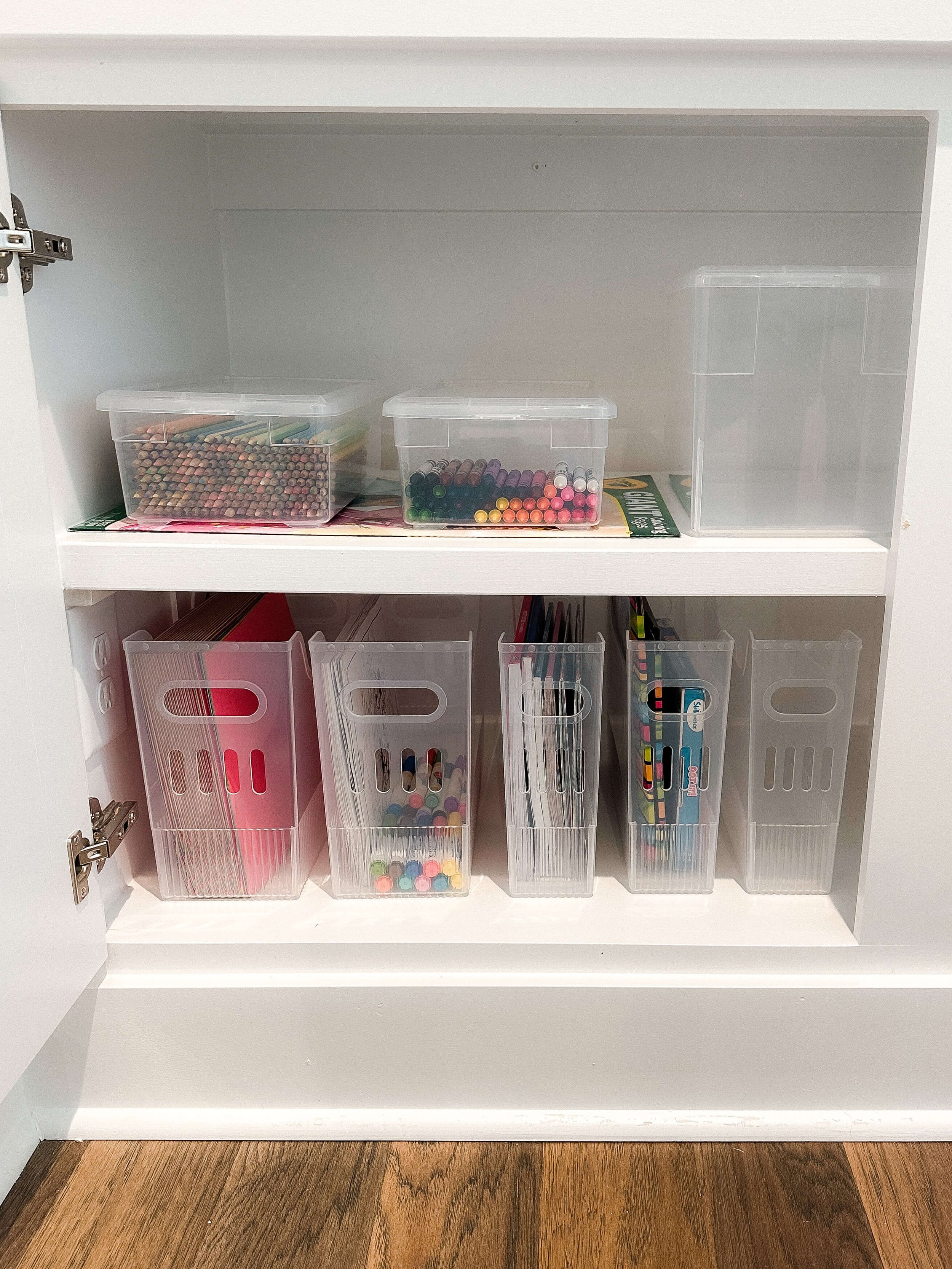 Cabinet with organized craft supplies, markers, paper, and coloring materials