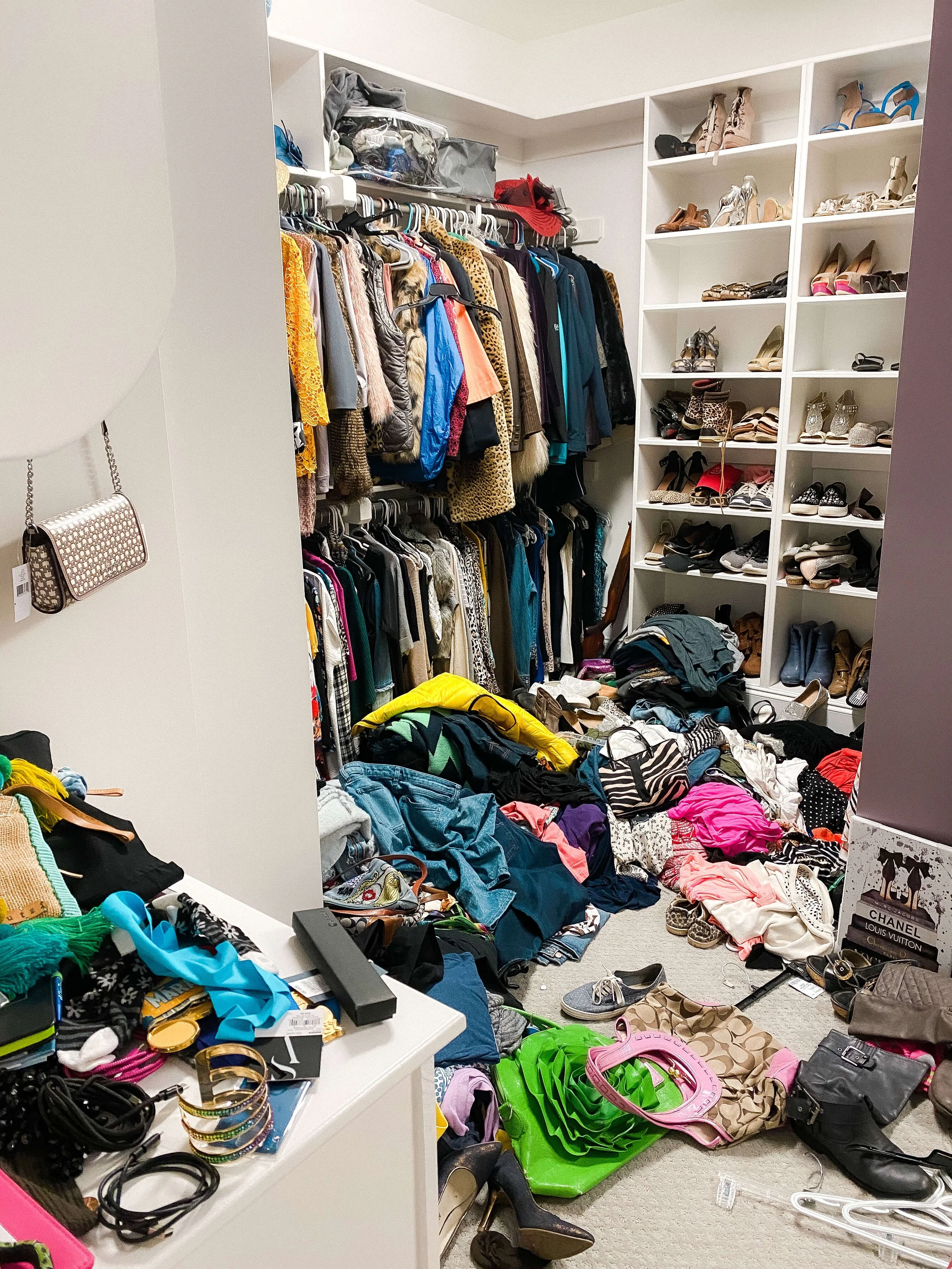 Walk-in closet before organizing with clothing, shoes, and accessories scattered across the floor