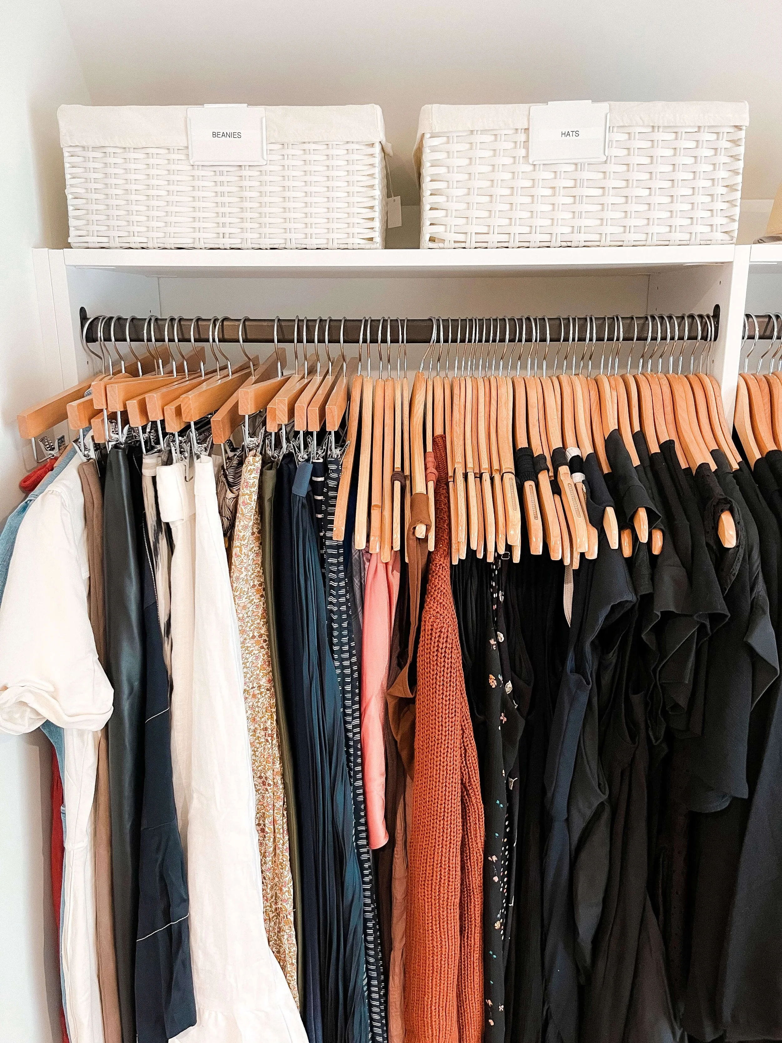 Closet shelf with labeled bins for beanies and hats above organized hanging clothes