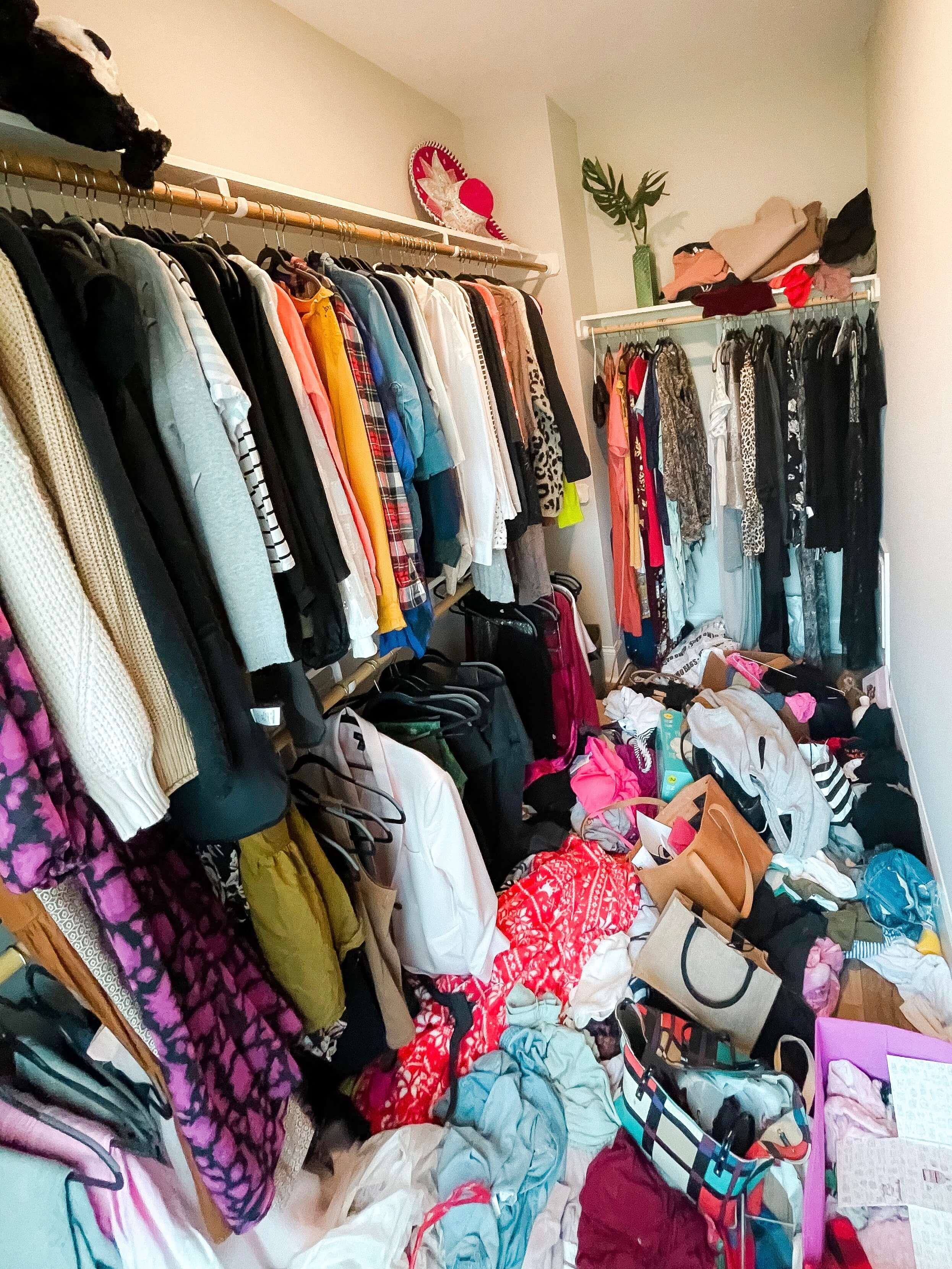 Primary closet before organizing with shoes, clothing, and accessories in an unfinished layout.