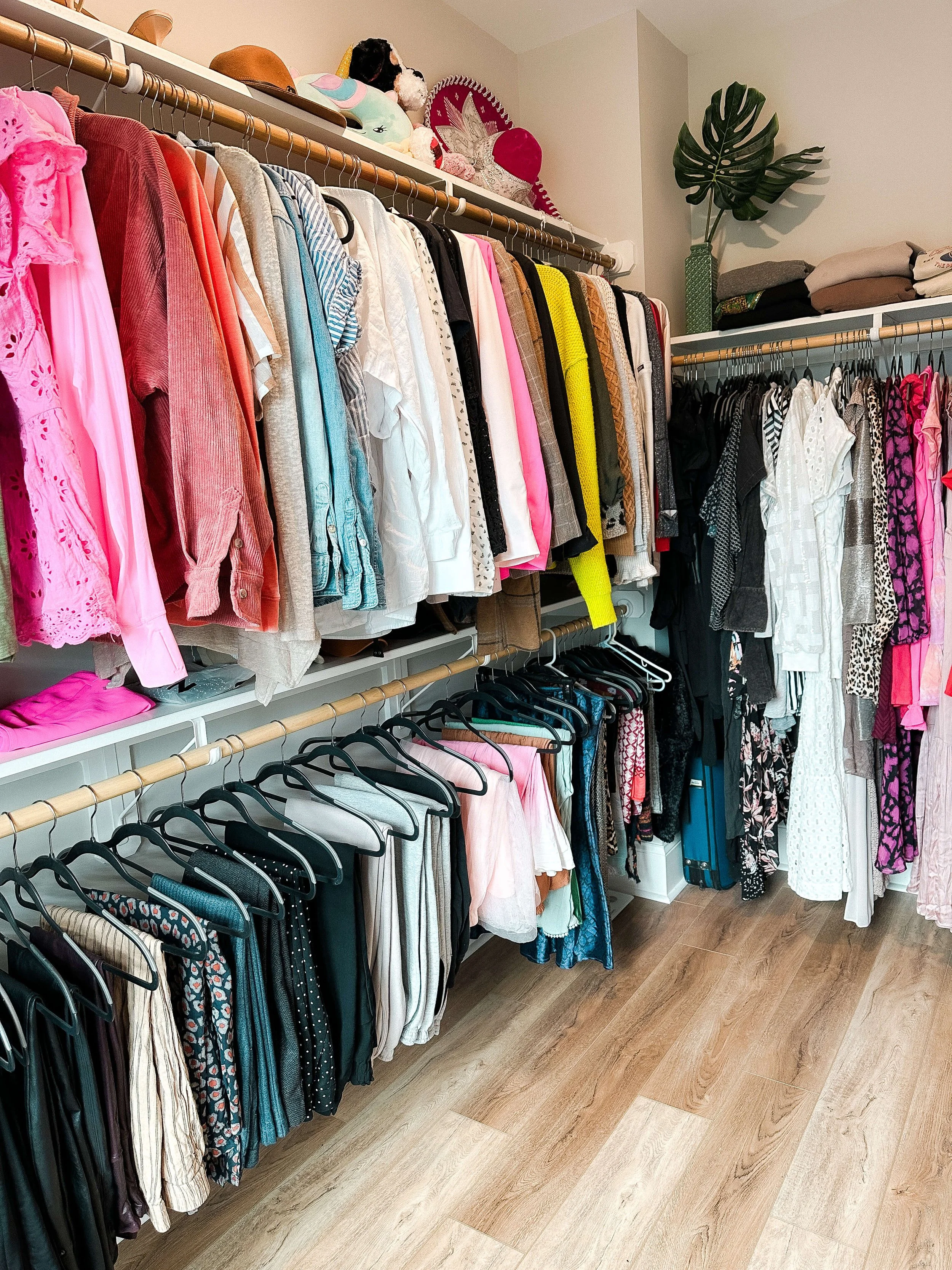 Organized primary closet with clothing grouped by category and color and shoes neatly arranged on shelves.