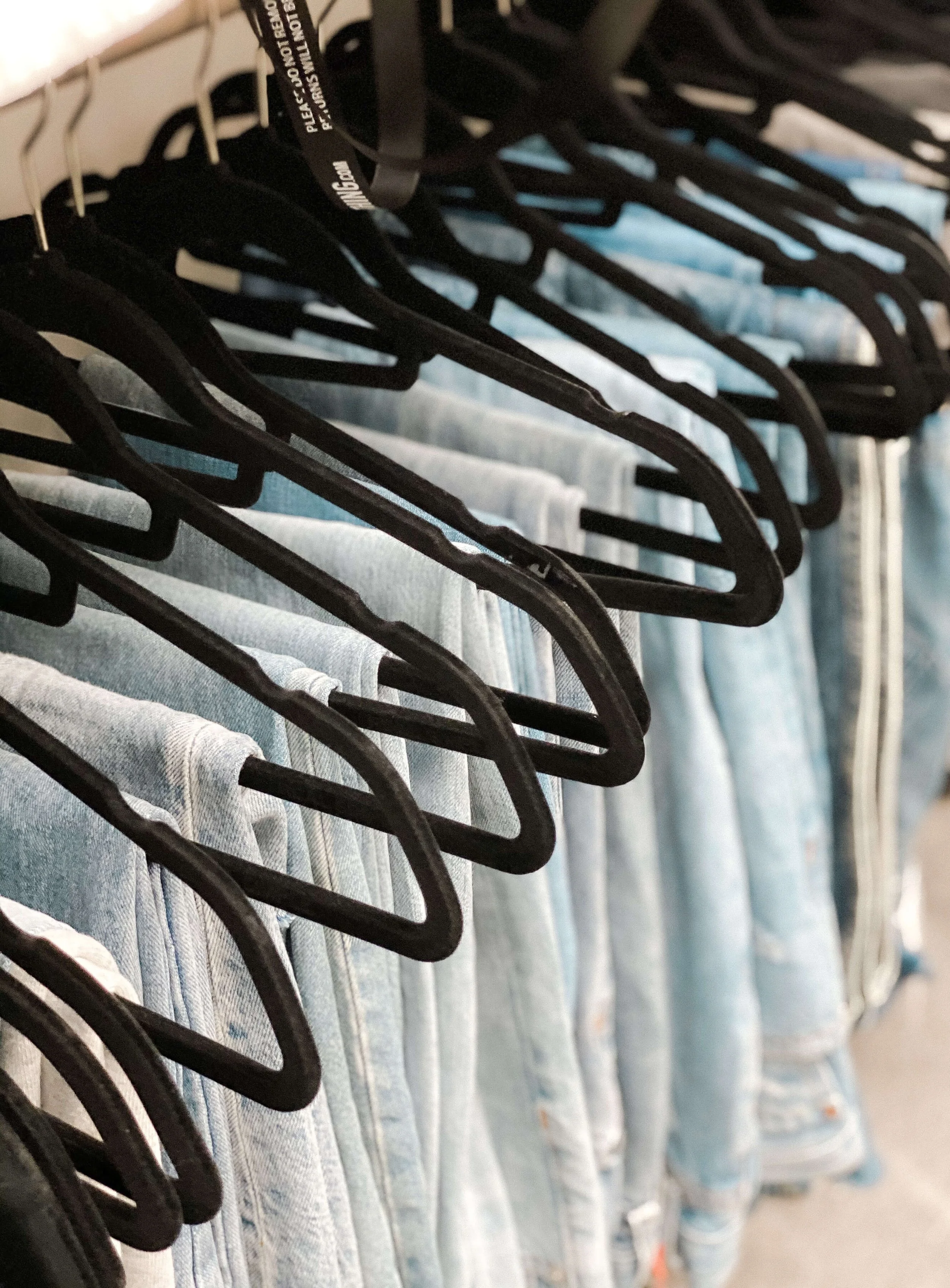 Clothing hanging on matching black velvet hangers inside an organized closet.