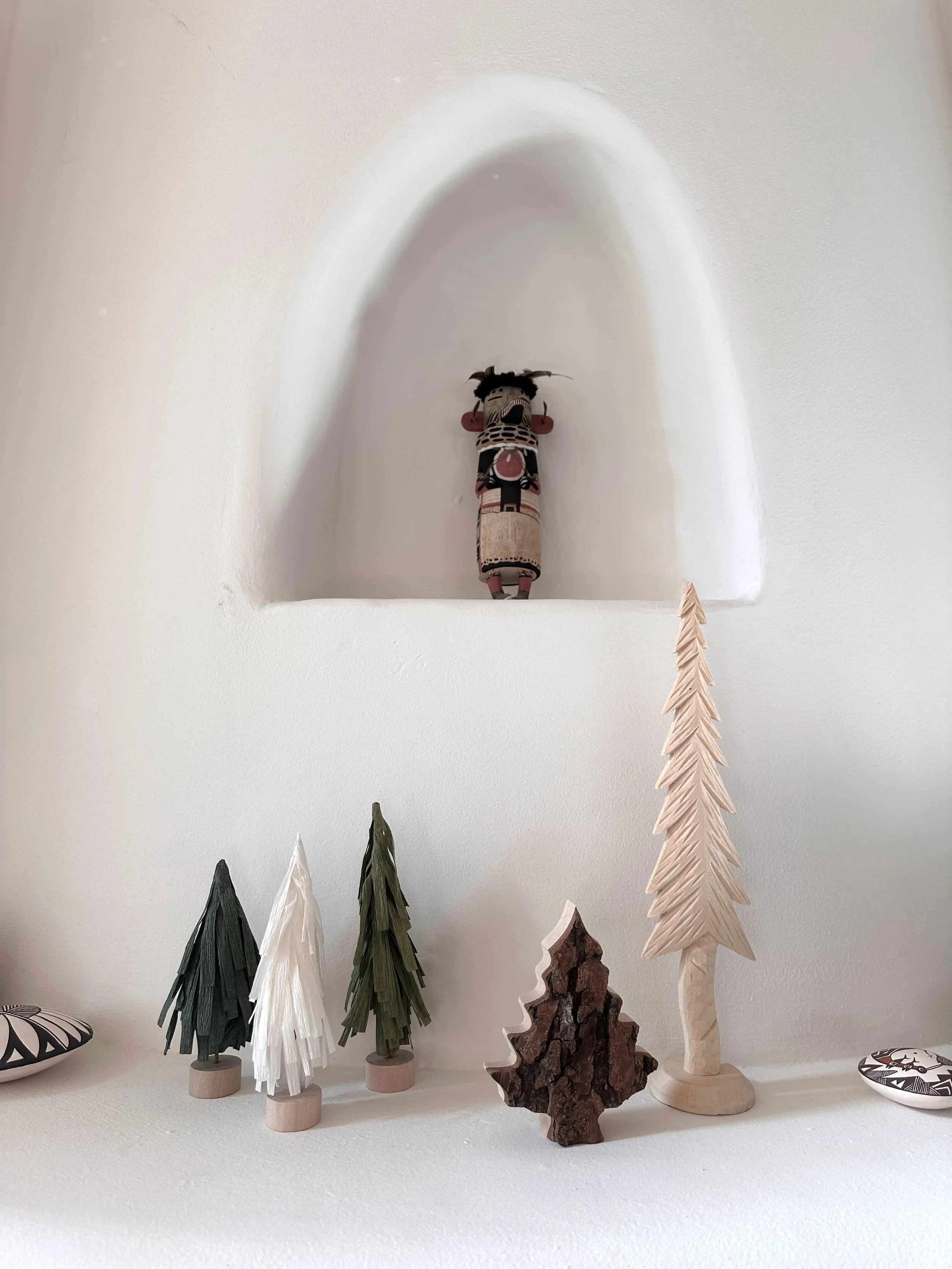  Carved and paper Christmas trees in an adobe niche with Pueblo pottery 
