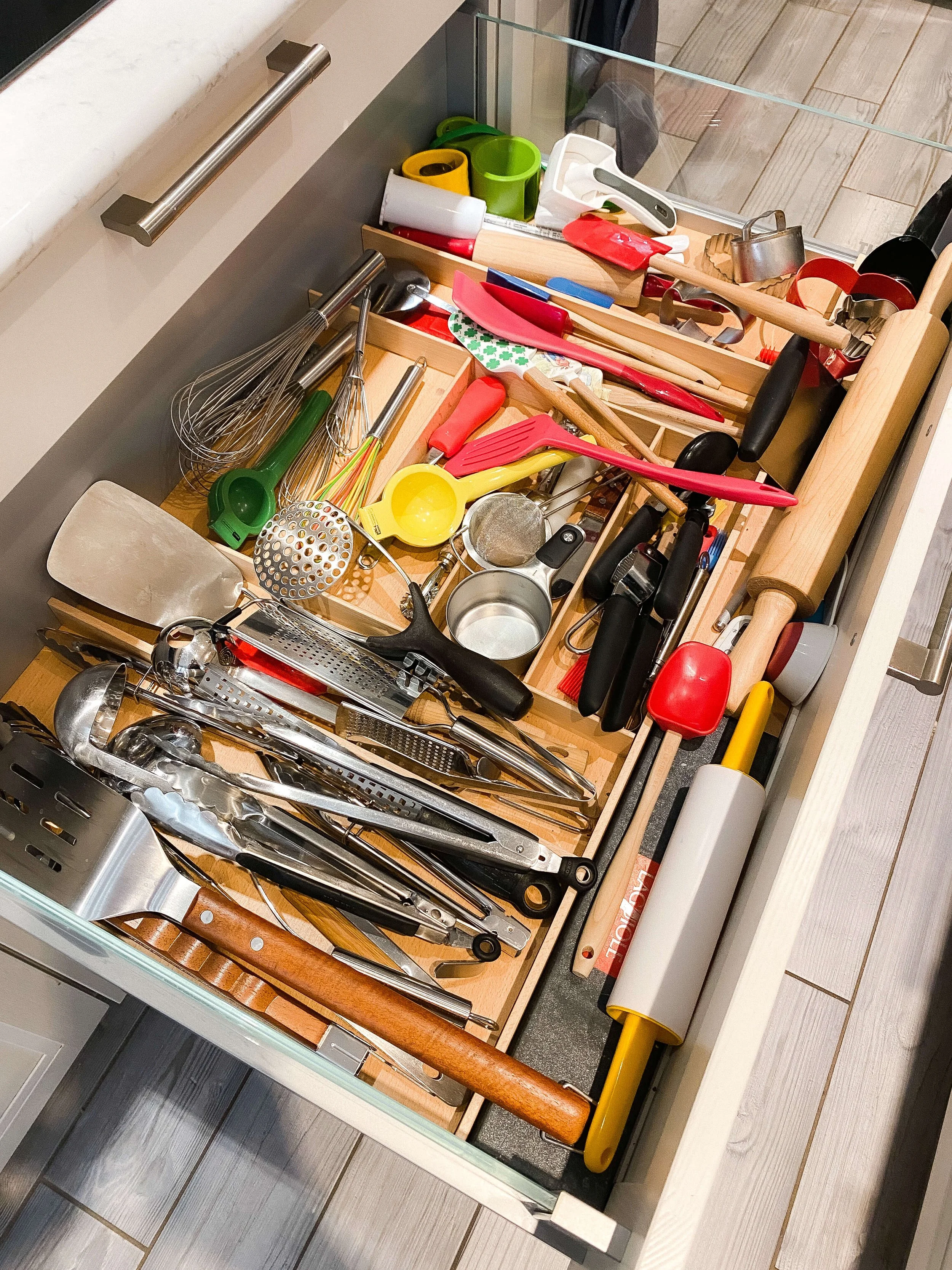  Cluttered Charlotte kitchen drawer with utensils piled together before organizing. 