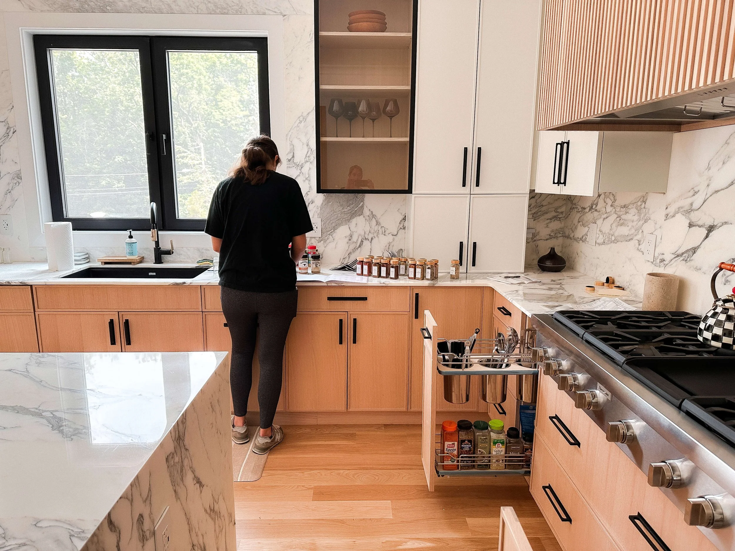 A Simplify Studio organizer arranging spices in a Charlotte kitchen with pull-out spice storage.