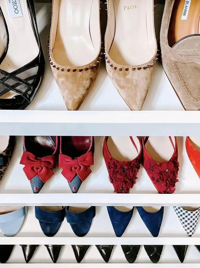 Organized shoe collection displayed neatly on white shelves, with women's heels arranged by color and style.