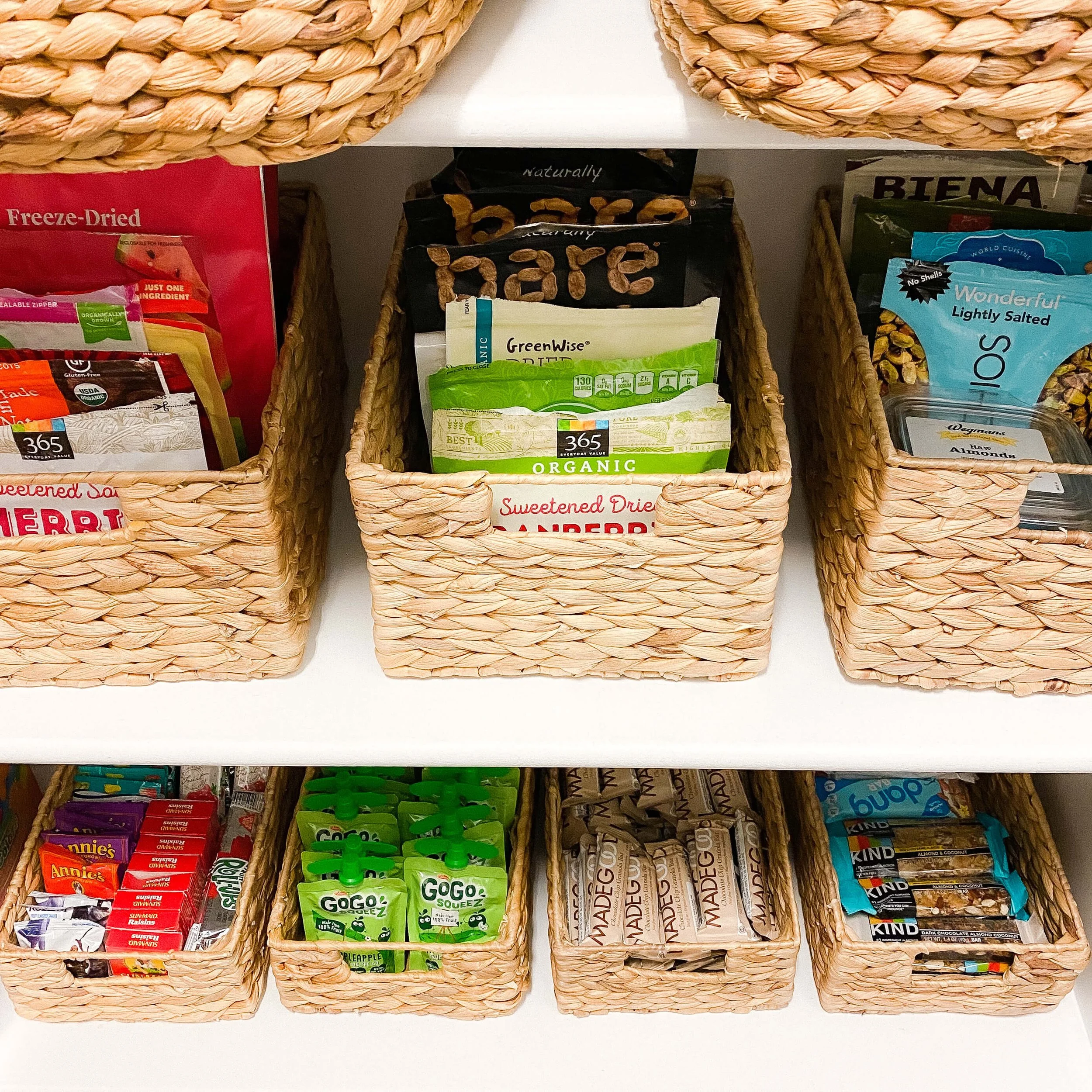Close-up of labeled woven baskets holding dried fruit, granola bars, and snack pouches
