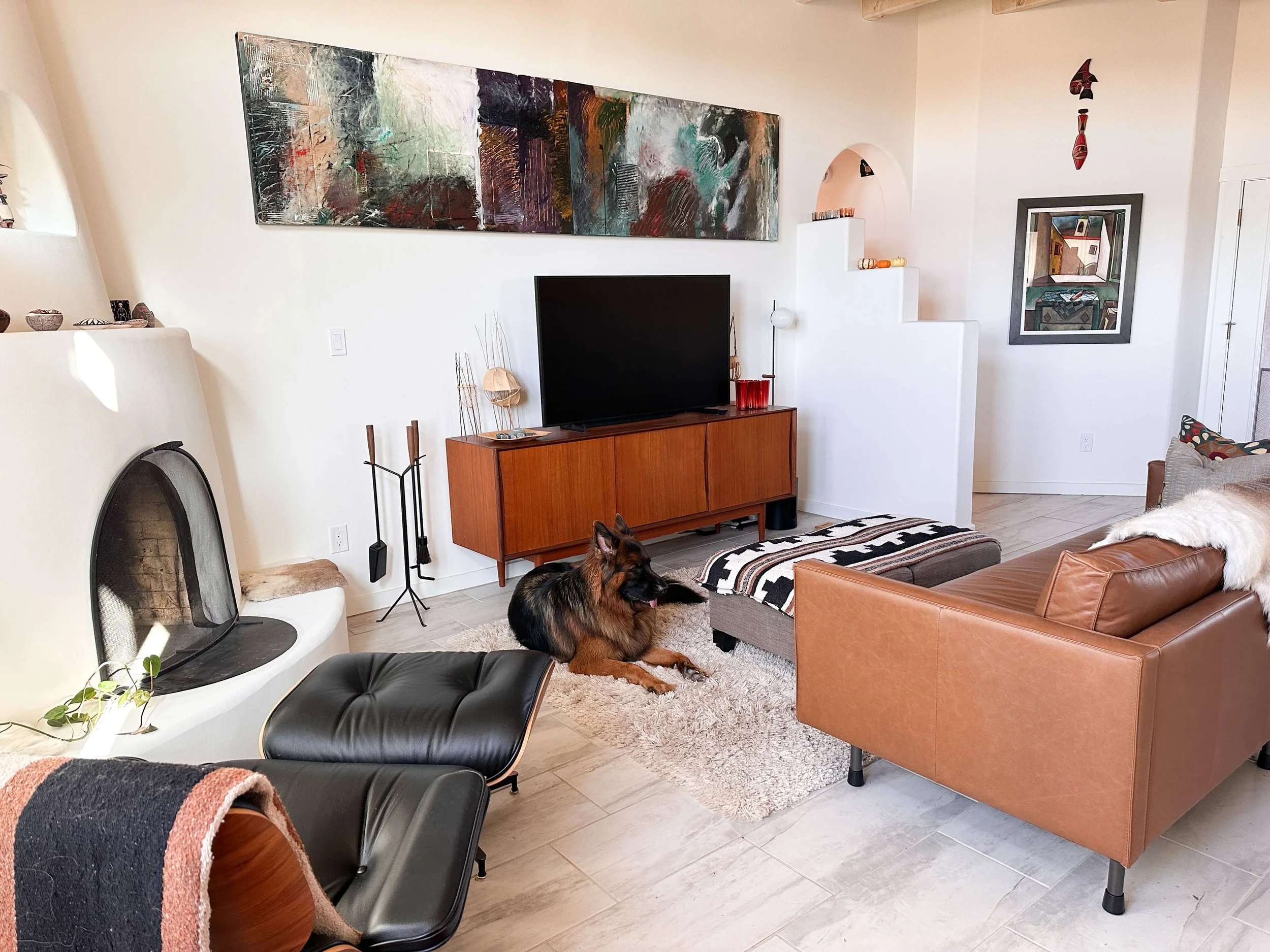 Organized Santa Fe living room with a kiva fireplace, mid-century media console, leather seating, and clear, open floor space.