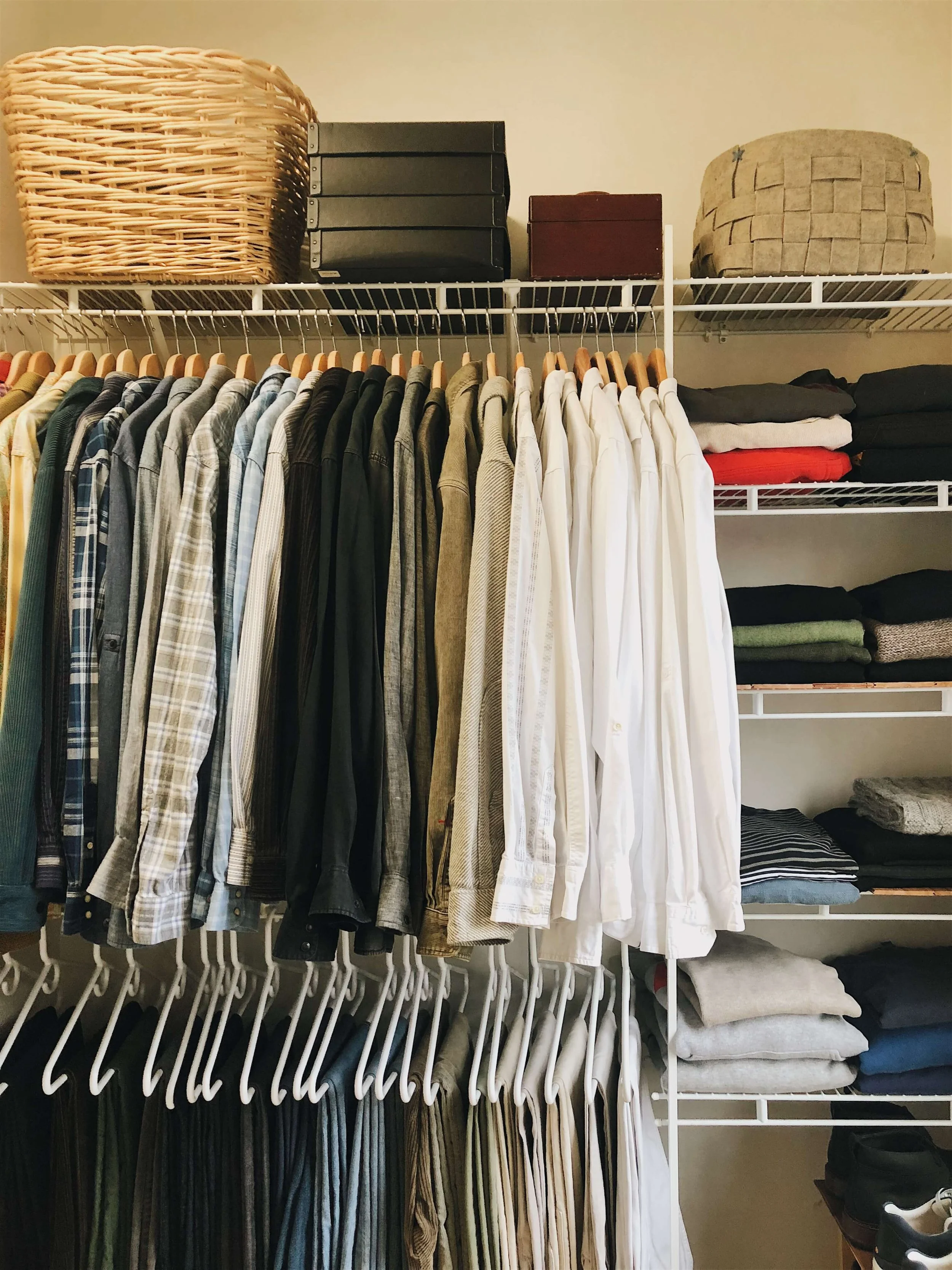 Professionally organized closet with hanging clothes, folded clothing, baskets, and storage boxes on shelves for seasonal wardrobe organization