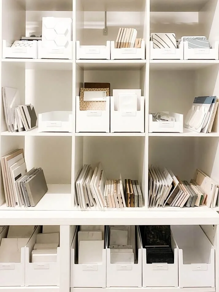 Interior design tile samples stored in white bins on open shelving.