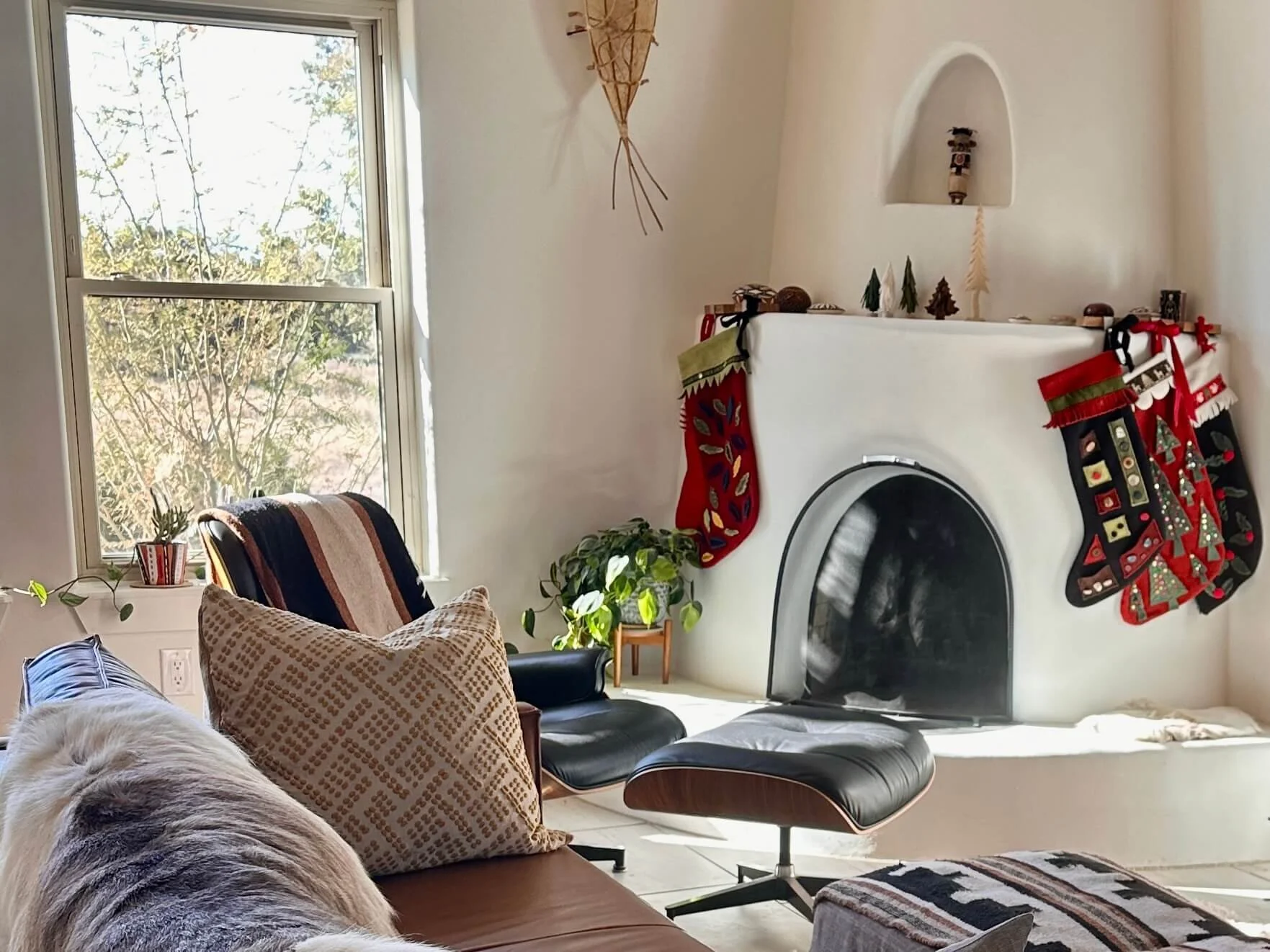 A sunlit Santa Fe living room with a kiva fireplace and hung holiday stockings