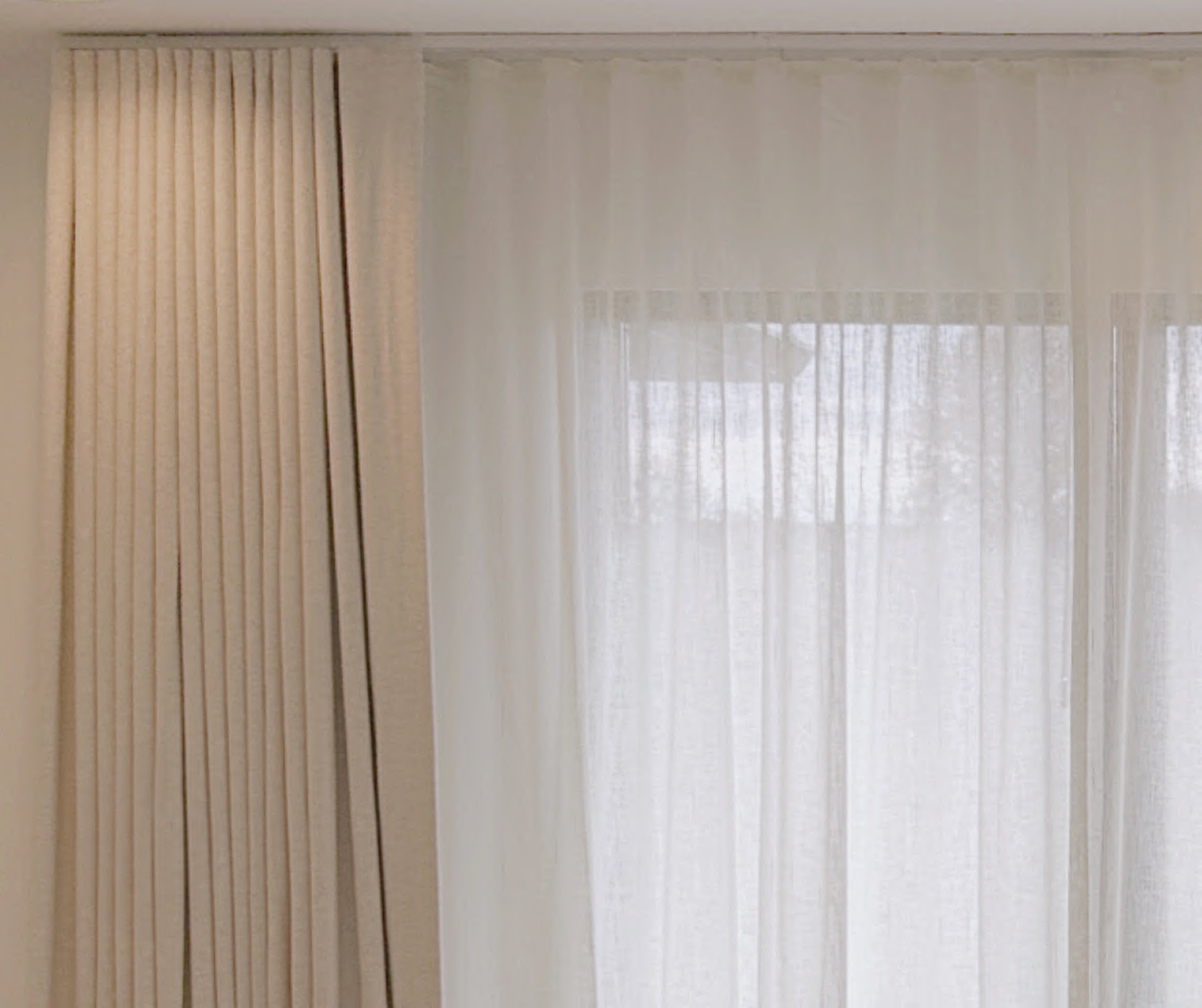 Traversing cream draperies over ethereal sheers for bedroom light control and privacy