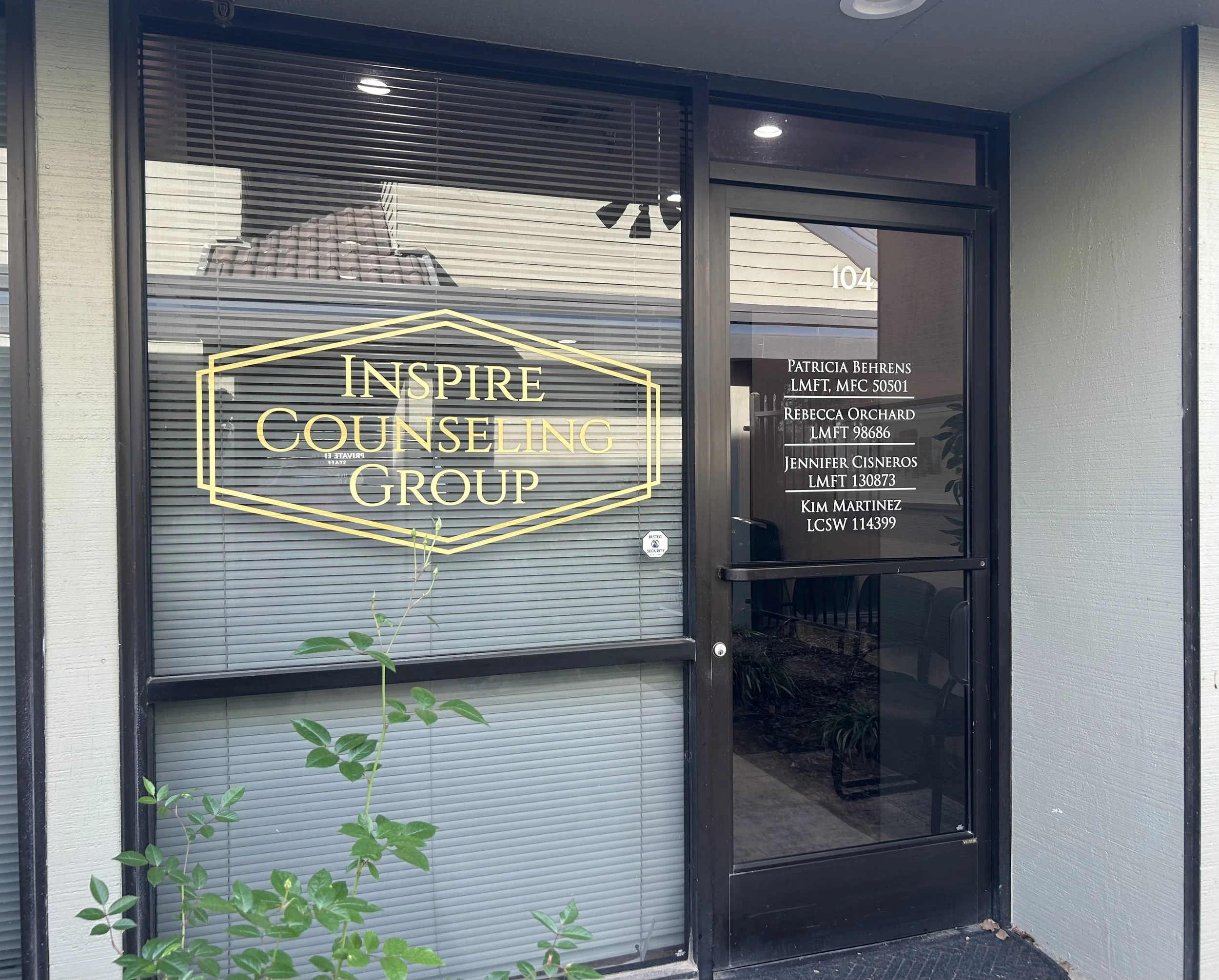 Office building entrance with window displaying 'Inspire Counseling Group' in gold lettering and list of staff names and credentials on the door beside it.