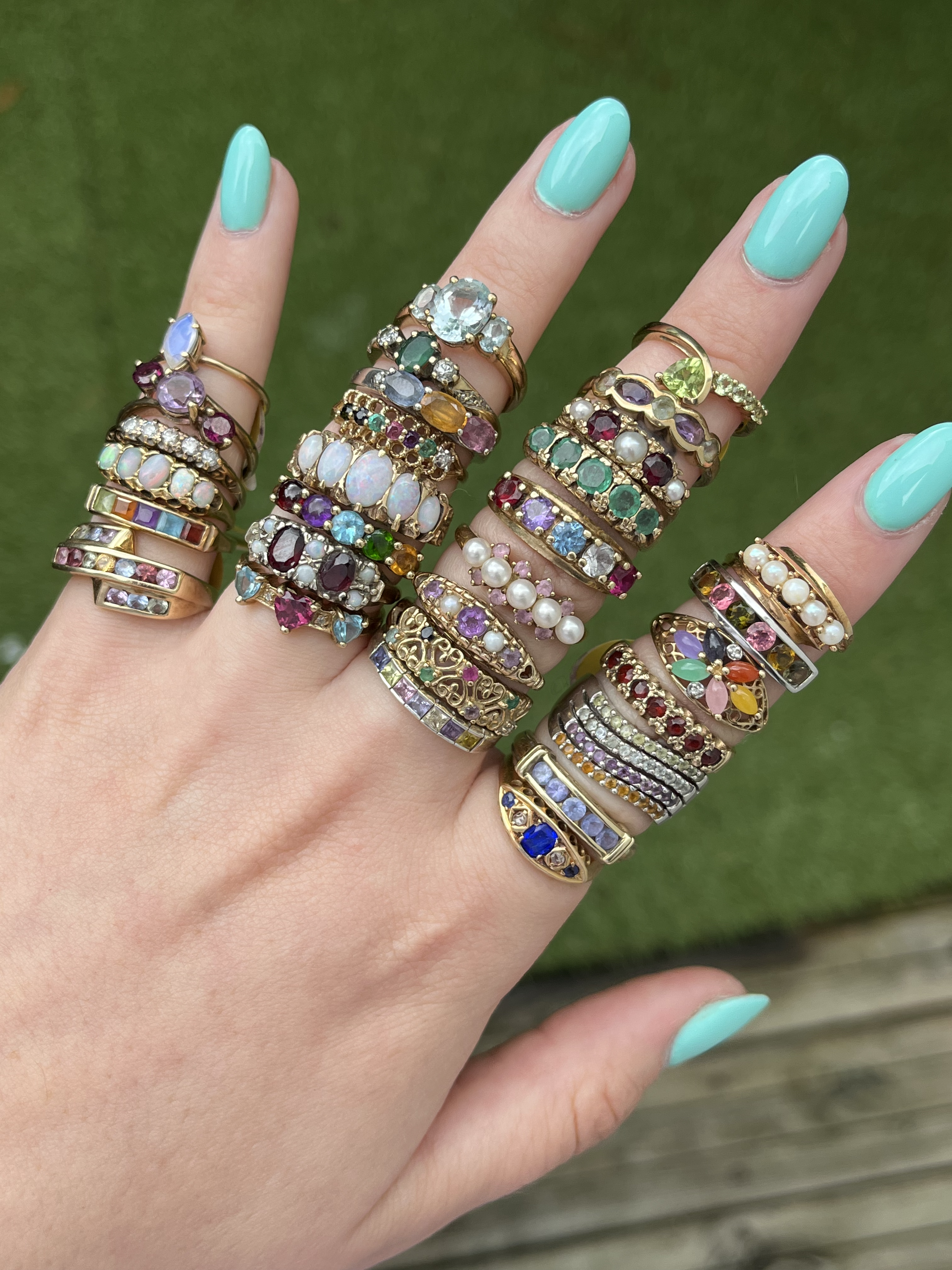 Close-up of hand wearing stacked vintage gemstone and gold rings from Sorrell Jewels, showcasing a vibrant and eclectic jewellery collection.