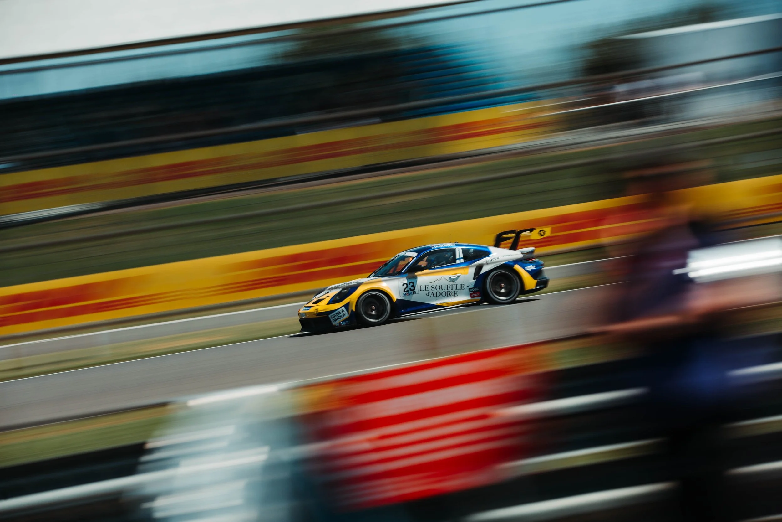 Race car speeding on a racetrack with blurred background and foreground, showing motion and speed.