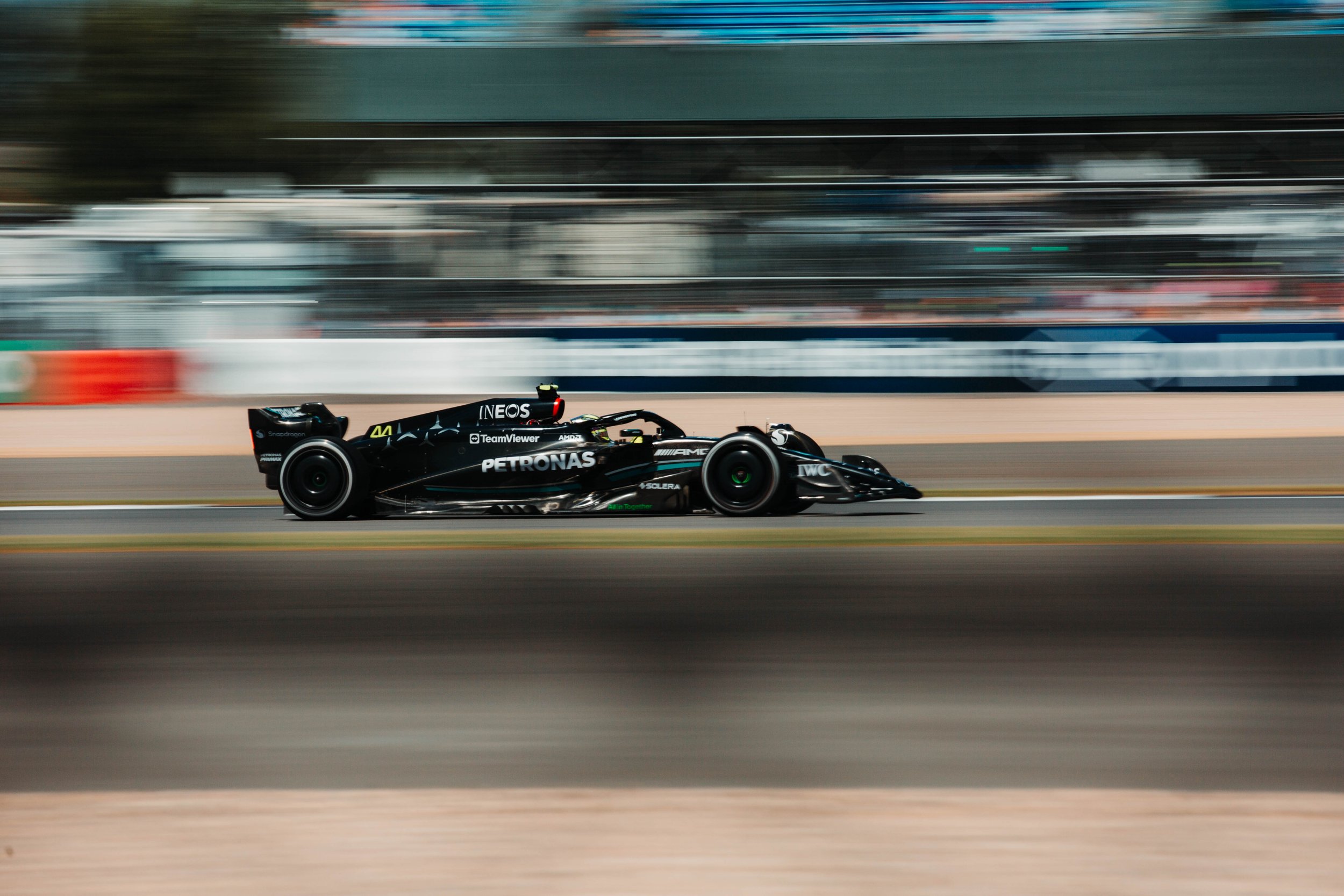 A black Formula 1 race car speeding on a racetrack with motion blur in the background.
