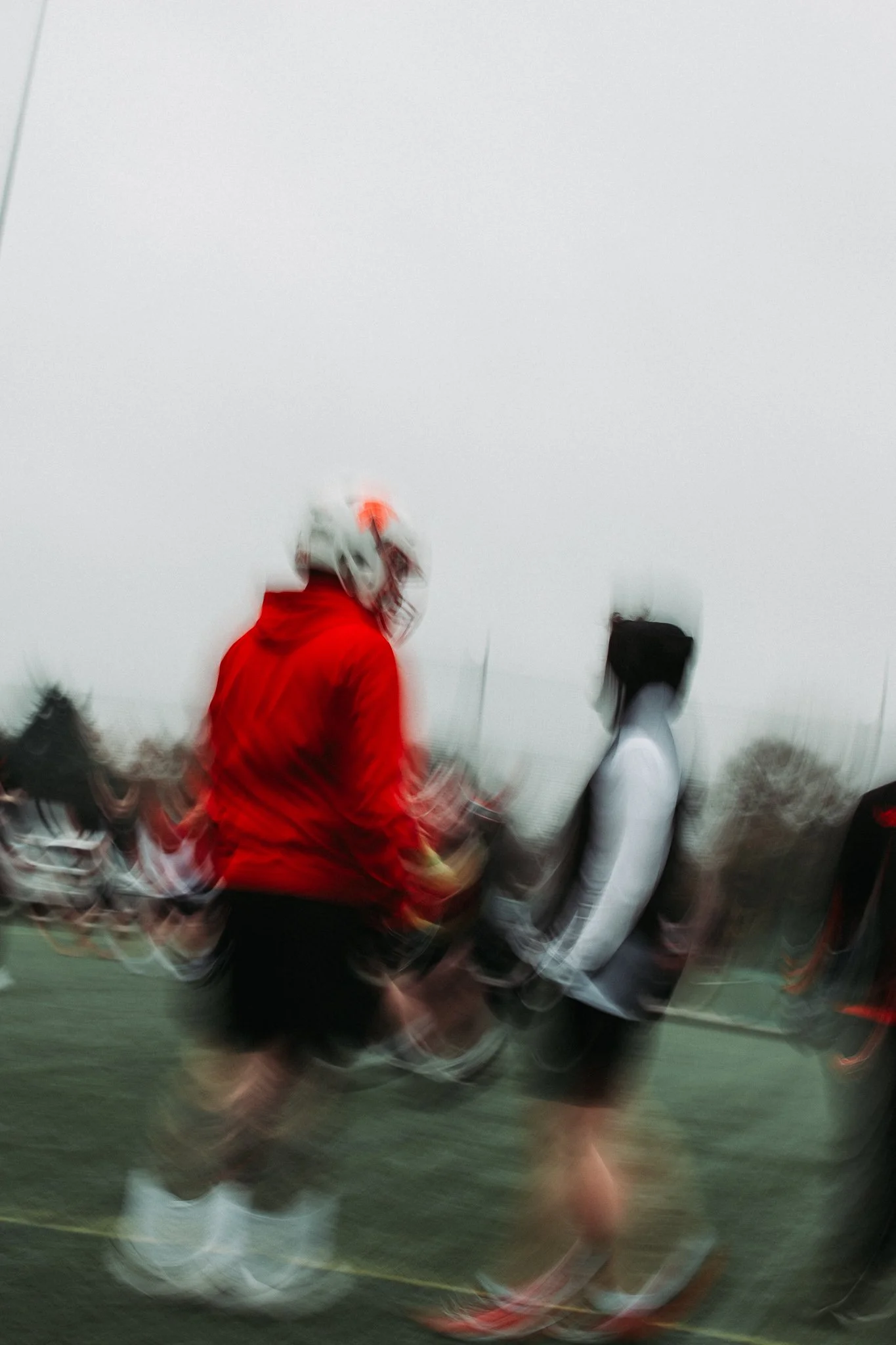 Two people standing on a football field with a foggy sky in the background, blurred due to motion.