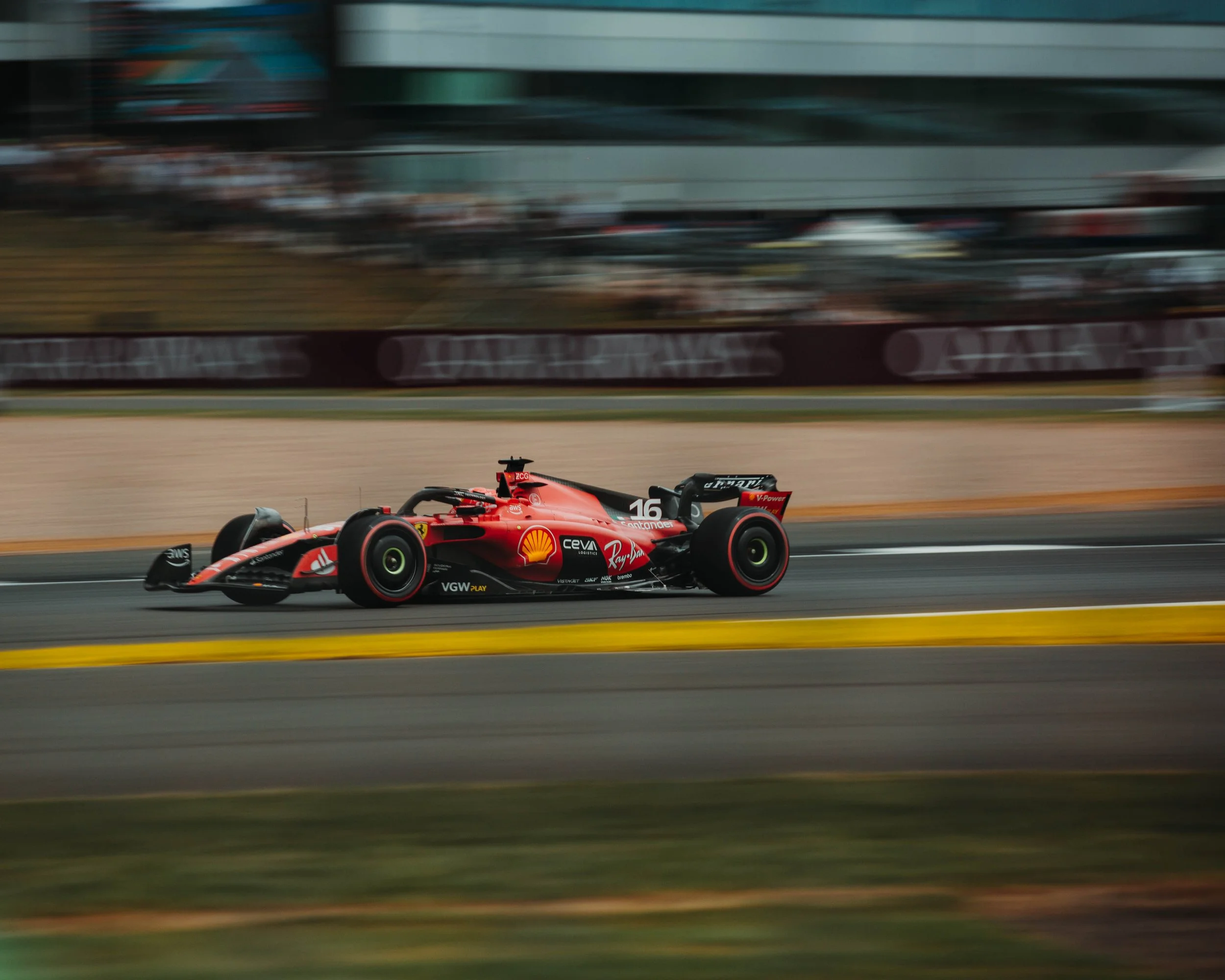 A red Formula 1 race car speeding on a track with motion blur in the background.