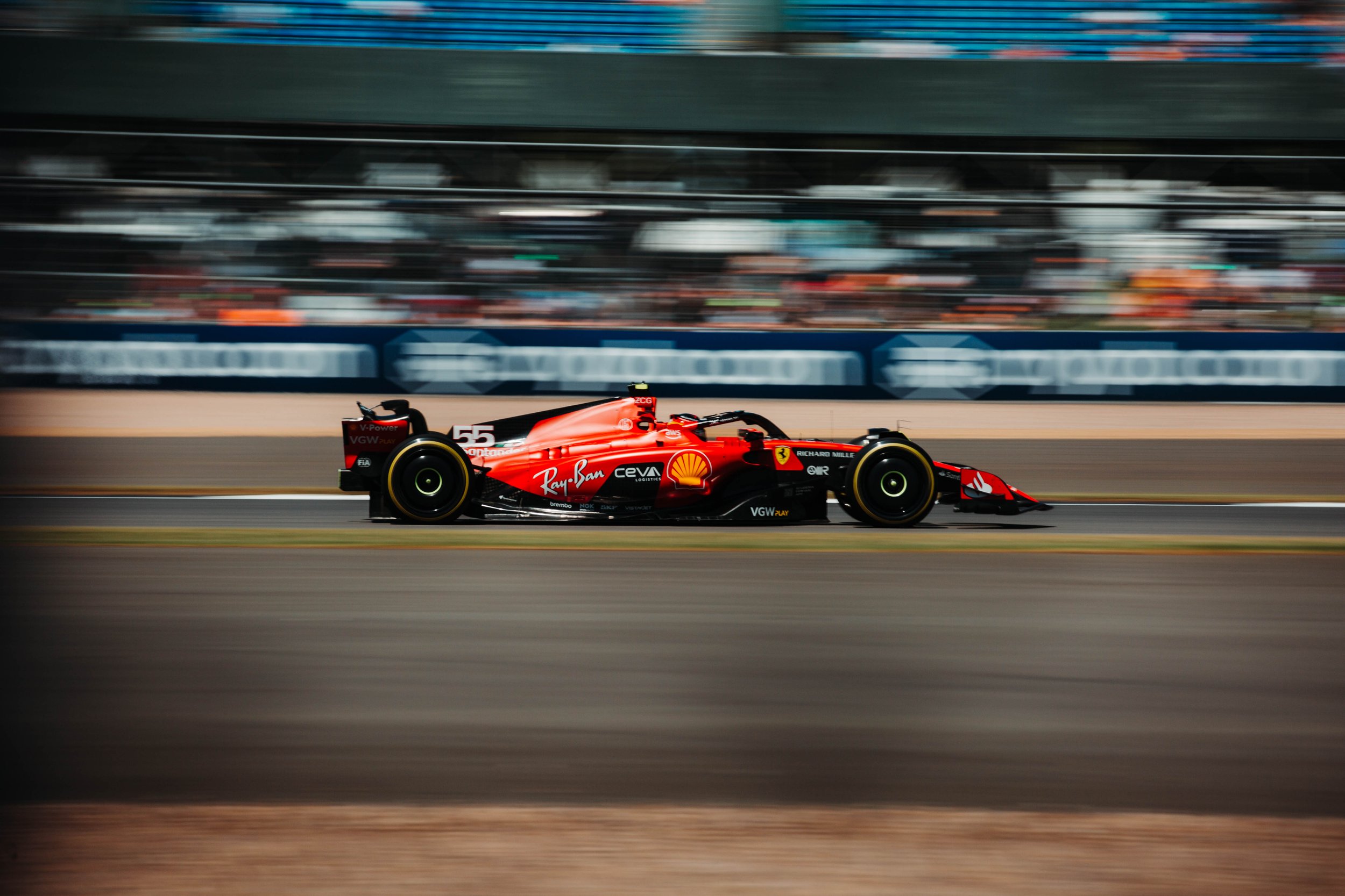 A red Formula 1 race car speeding on a race track with blurred background.
