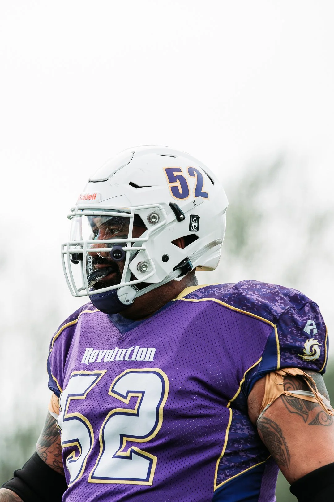 A football player wearing a purple jersey with the number 52 and a white helmet with the number 52, looking to the side.