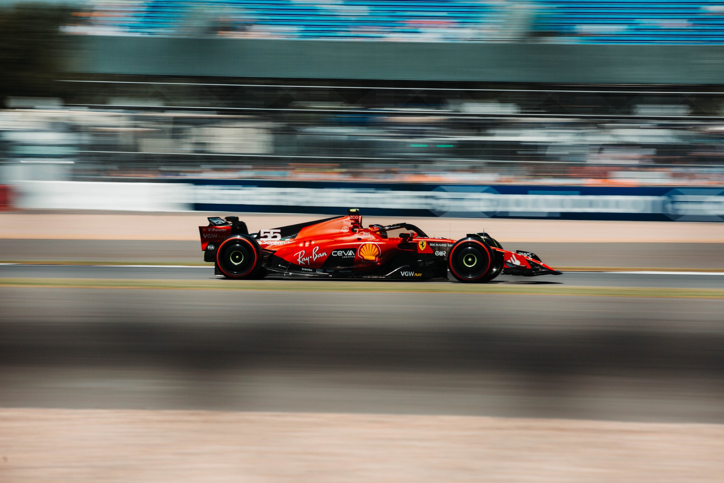 A red Formula 1 race car speeding on a racetrack with a blurred background.